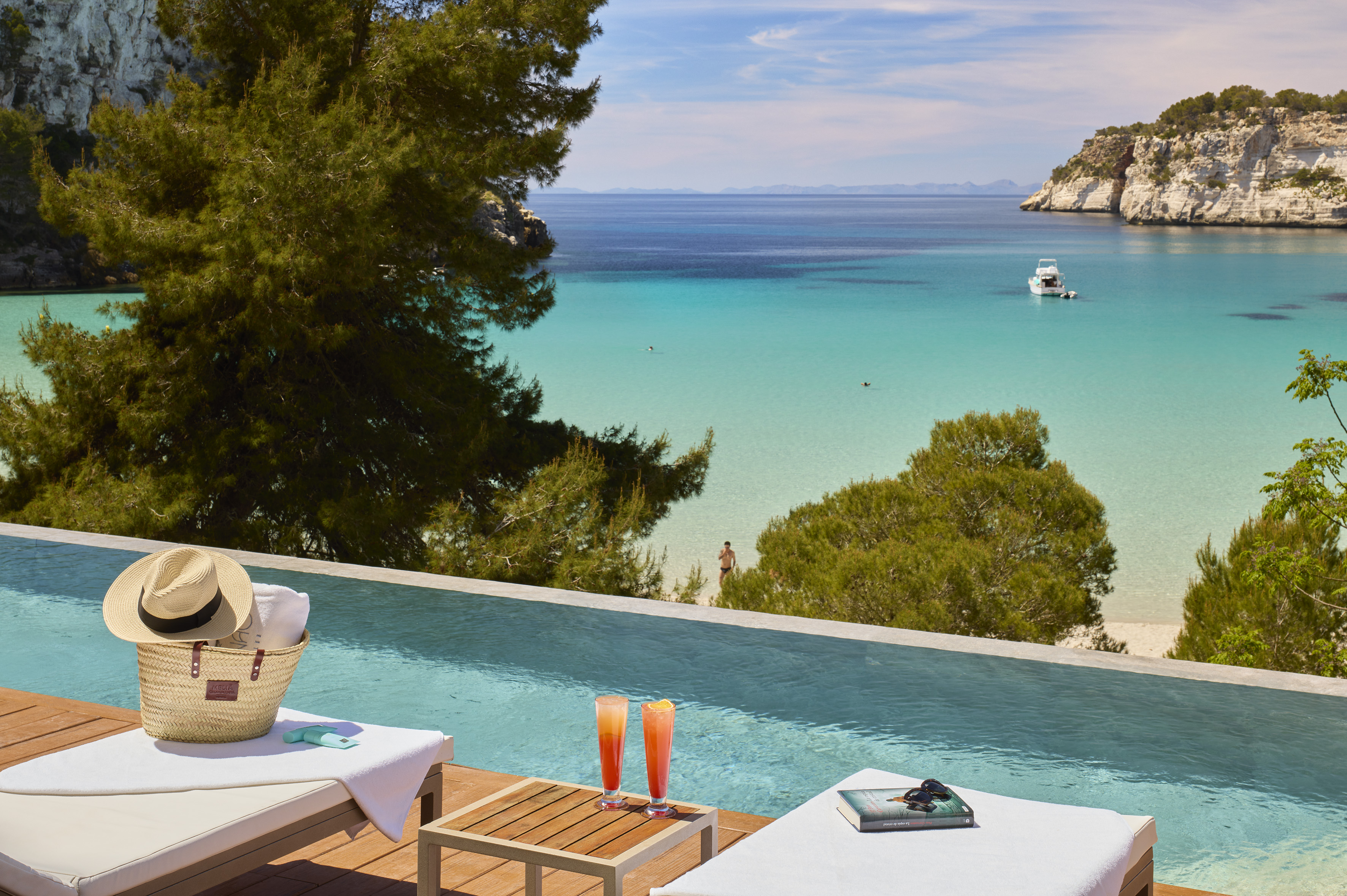 Luxury infinity pool, cocktails, lounge chairs overlooking turquoise bay.