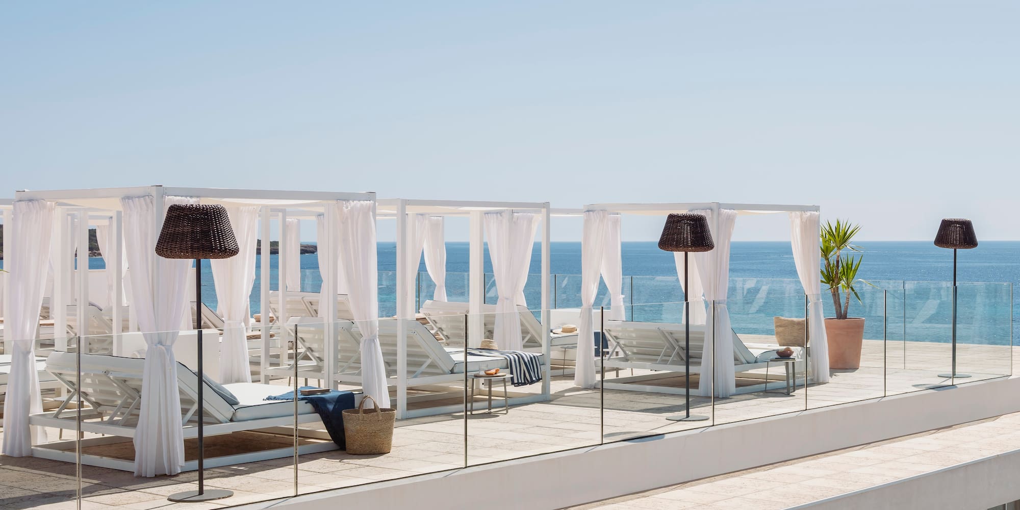 Terraza azotea de lujo con camas balinesas blancas y vistas al mar.