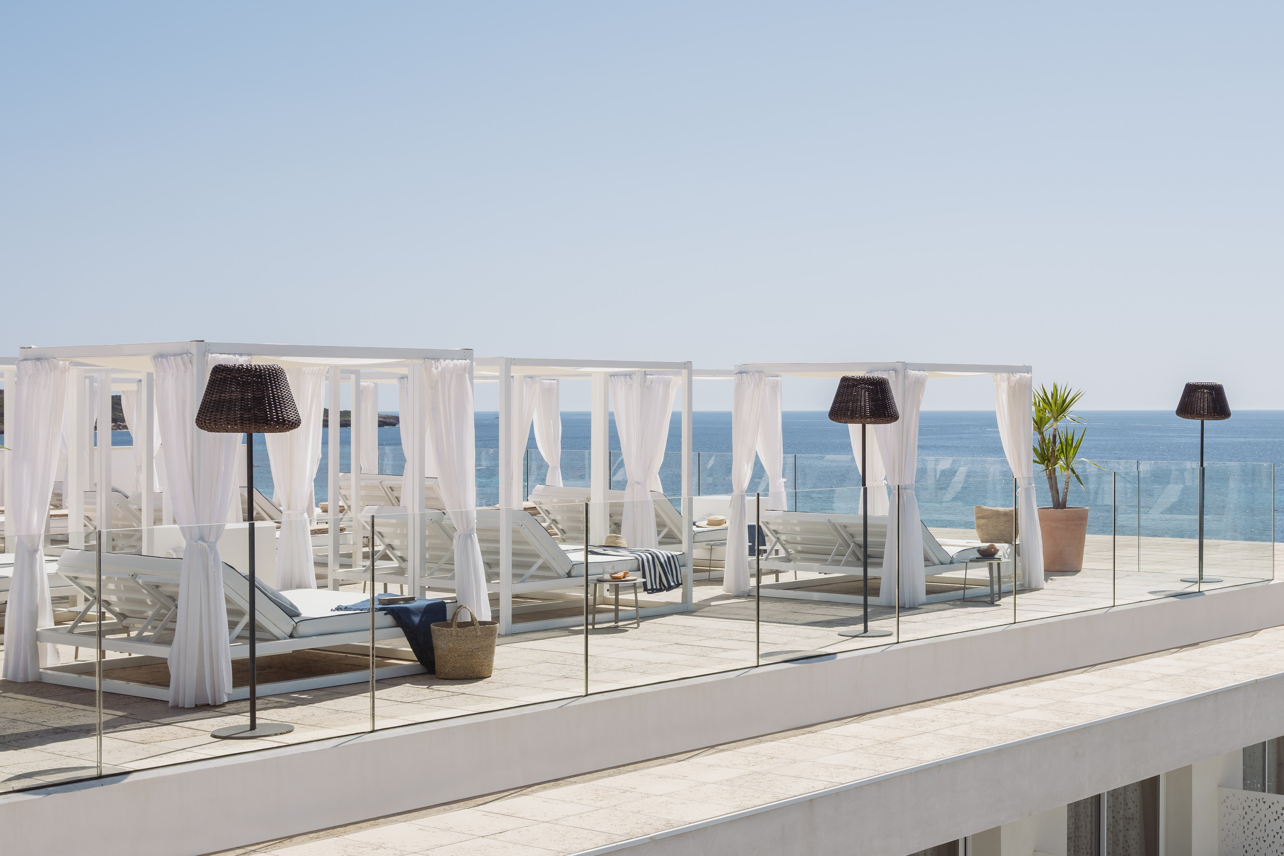 Terraza azotea de lujo con camas balinesas blancas y vistas al mar.