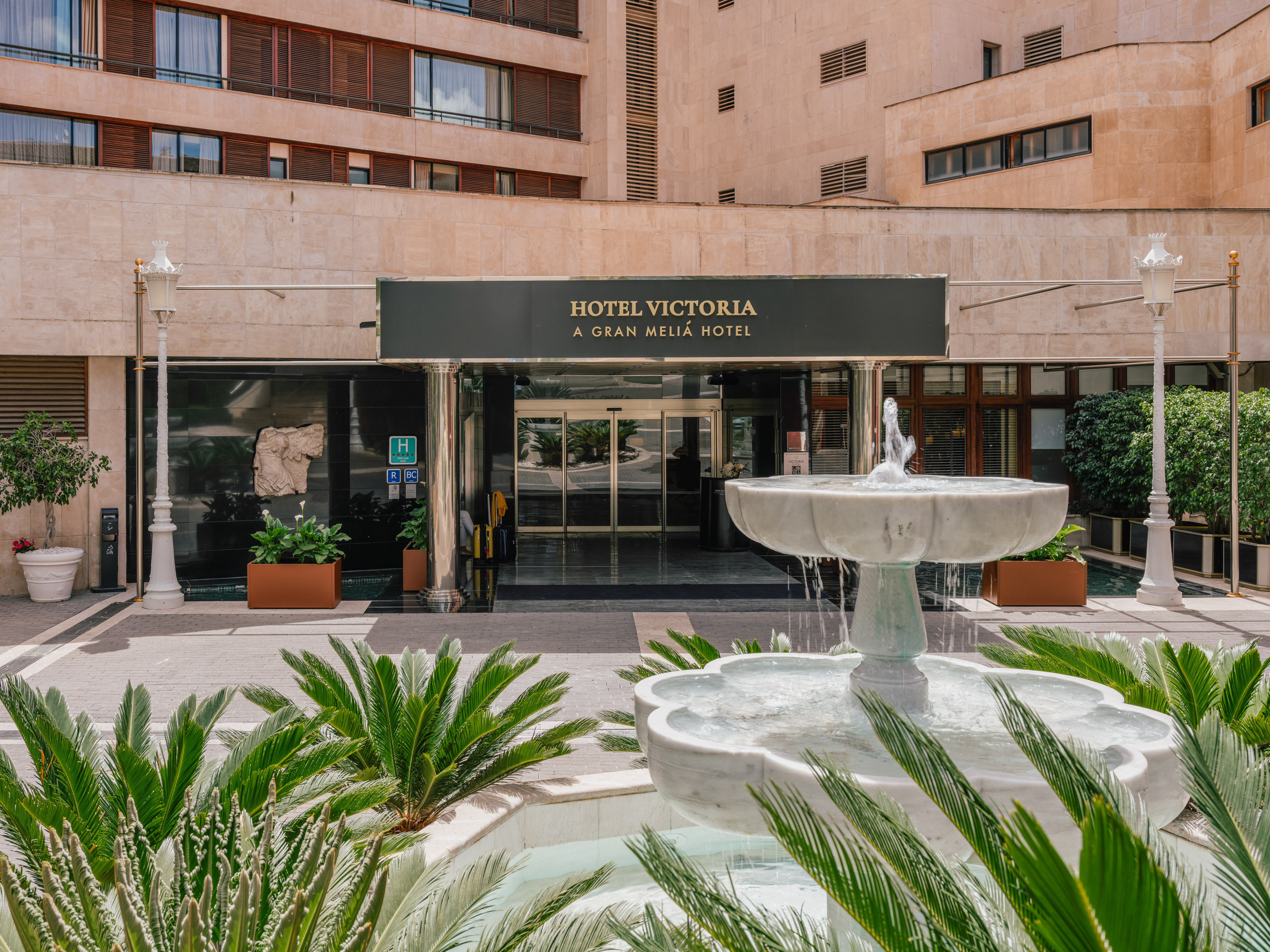 Hotel Victoria Gran Meliá entrance with marble fountain and palm plants.