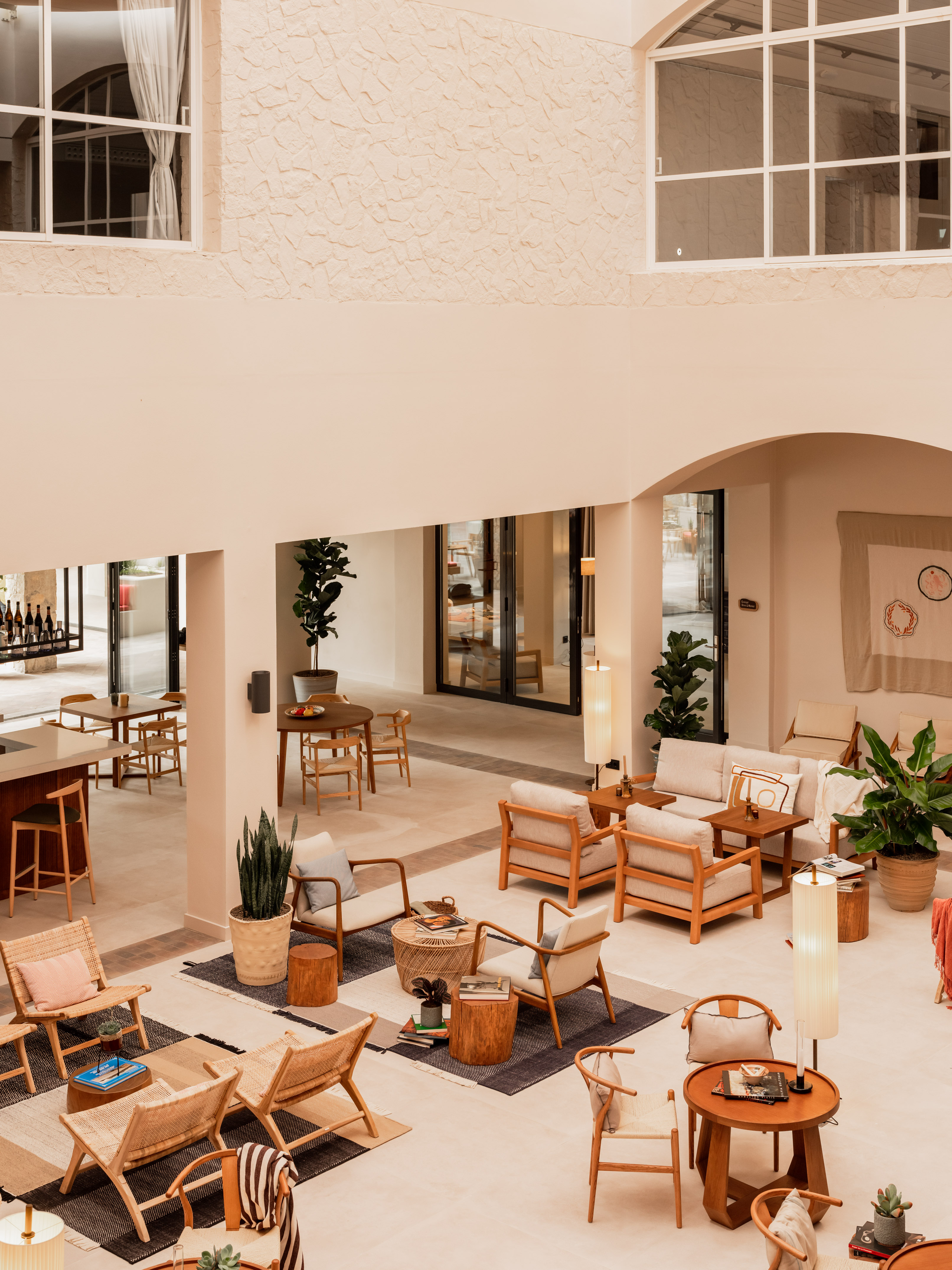Bright, modern hotel lounge with comfortable wooden seating and potted plants.