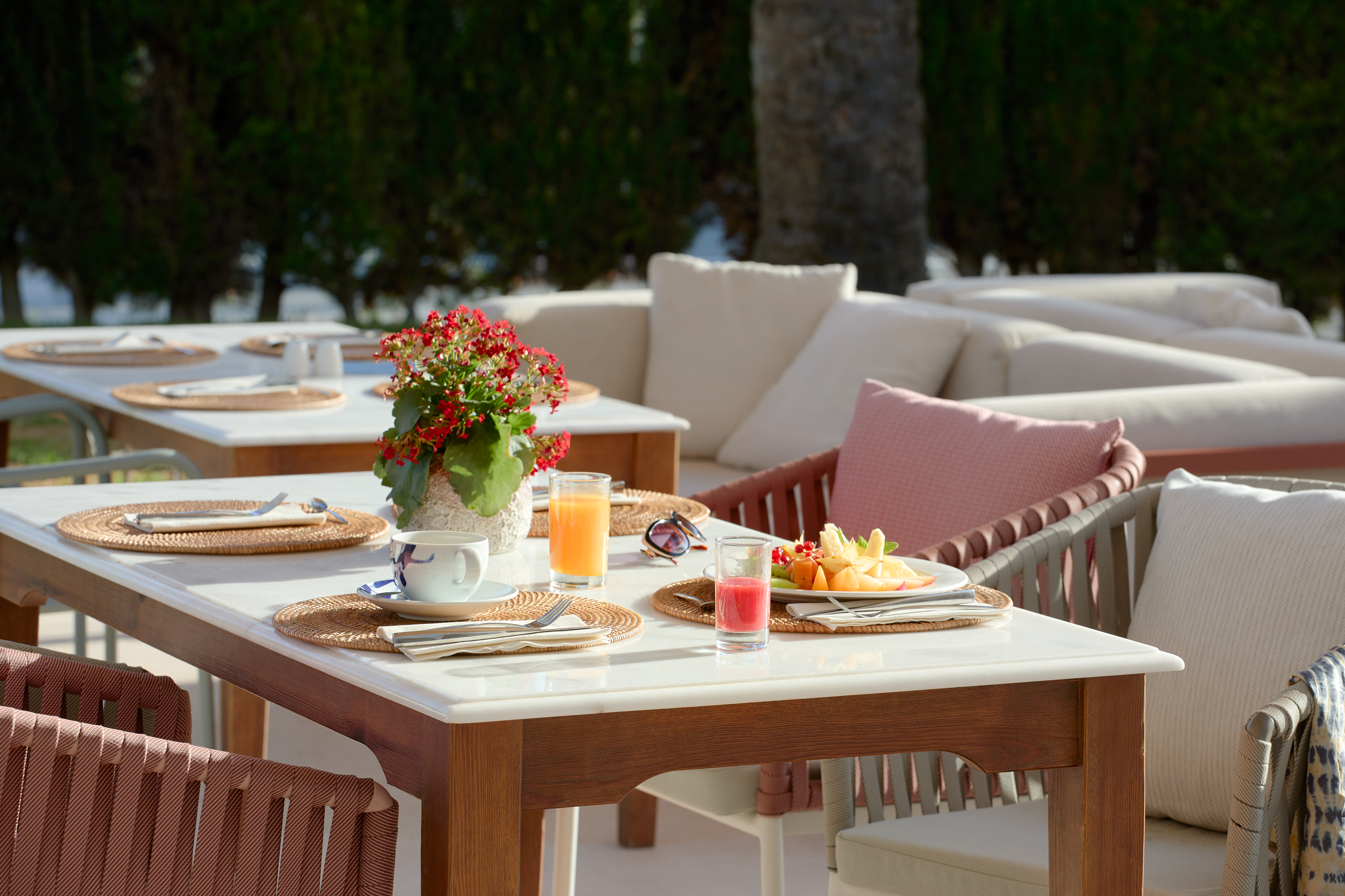 Outdoor resort breakfast table with fresh fruit, juices, and coffee.
