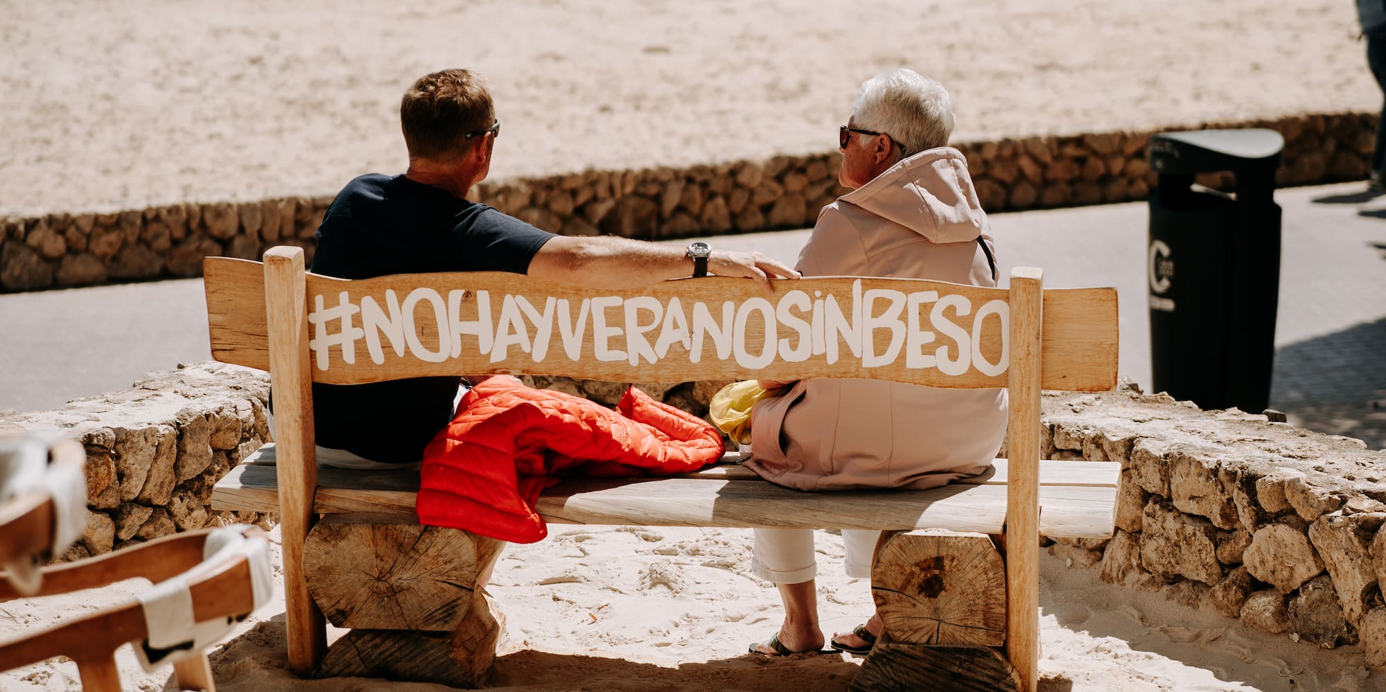 a man and woman sitting on a bench on a beach