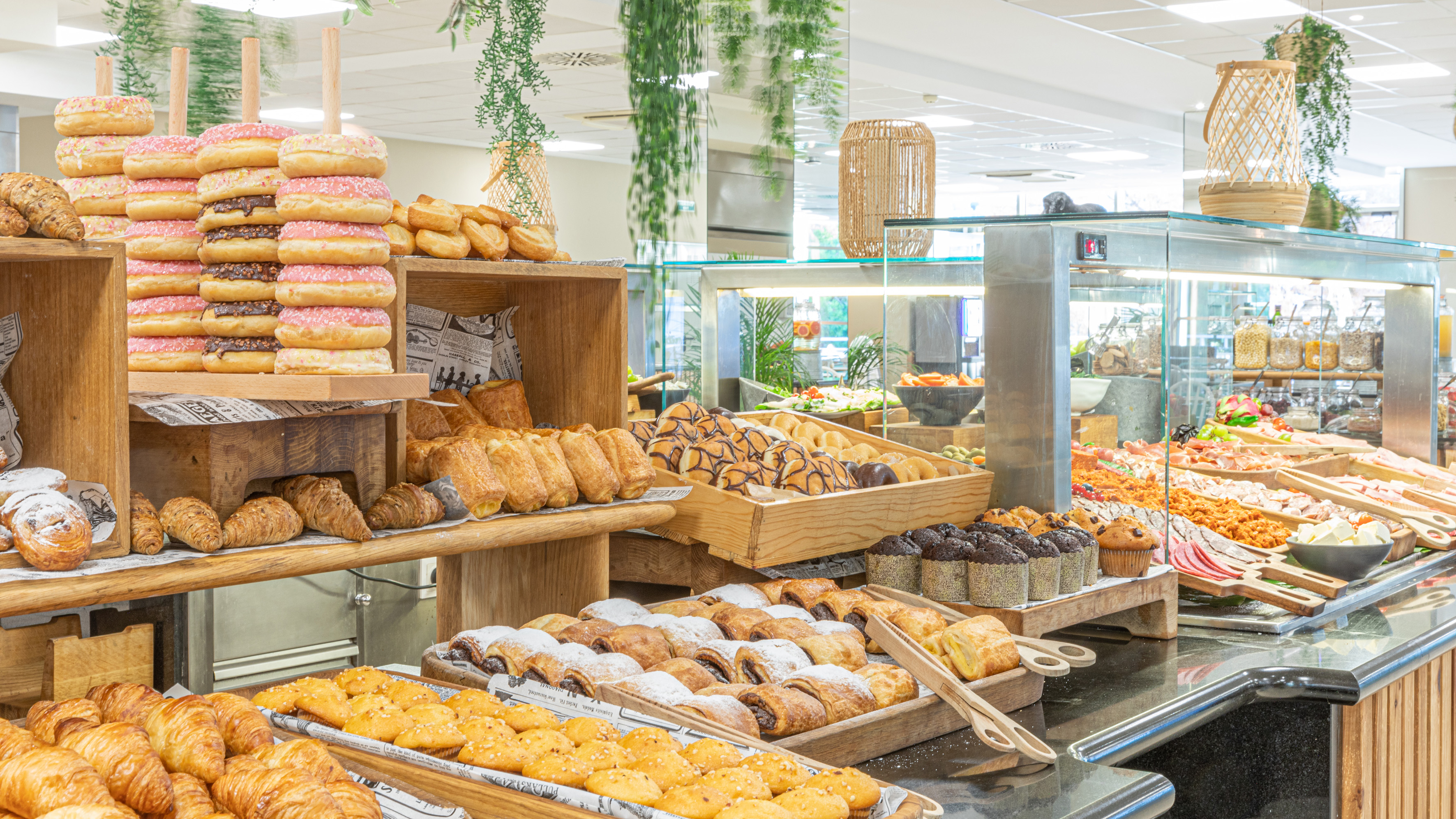 Hotel breakfast buffet with stacked donuts, croissants, pastries, and cereals.