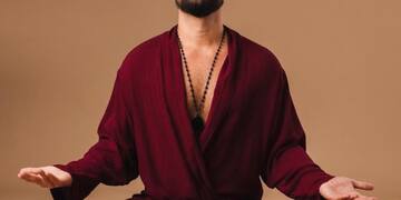 a man in a robe sitting cross legged with his eyes closed