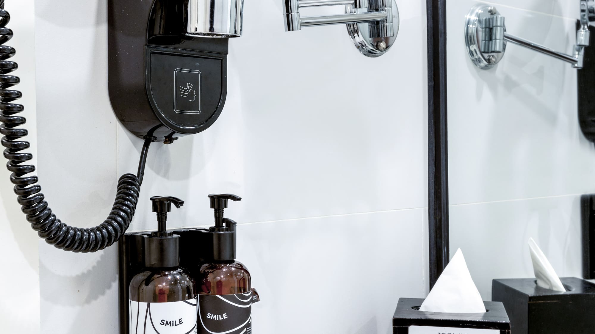 a black and white bathroom with a mirror and a black wall mounted hair dryer