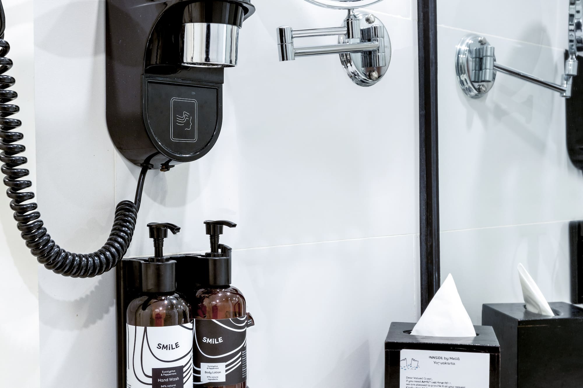 a black and white bathroom with a mirror and a black wall mounted hair dryer