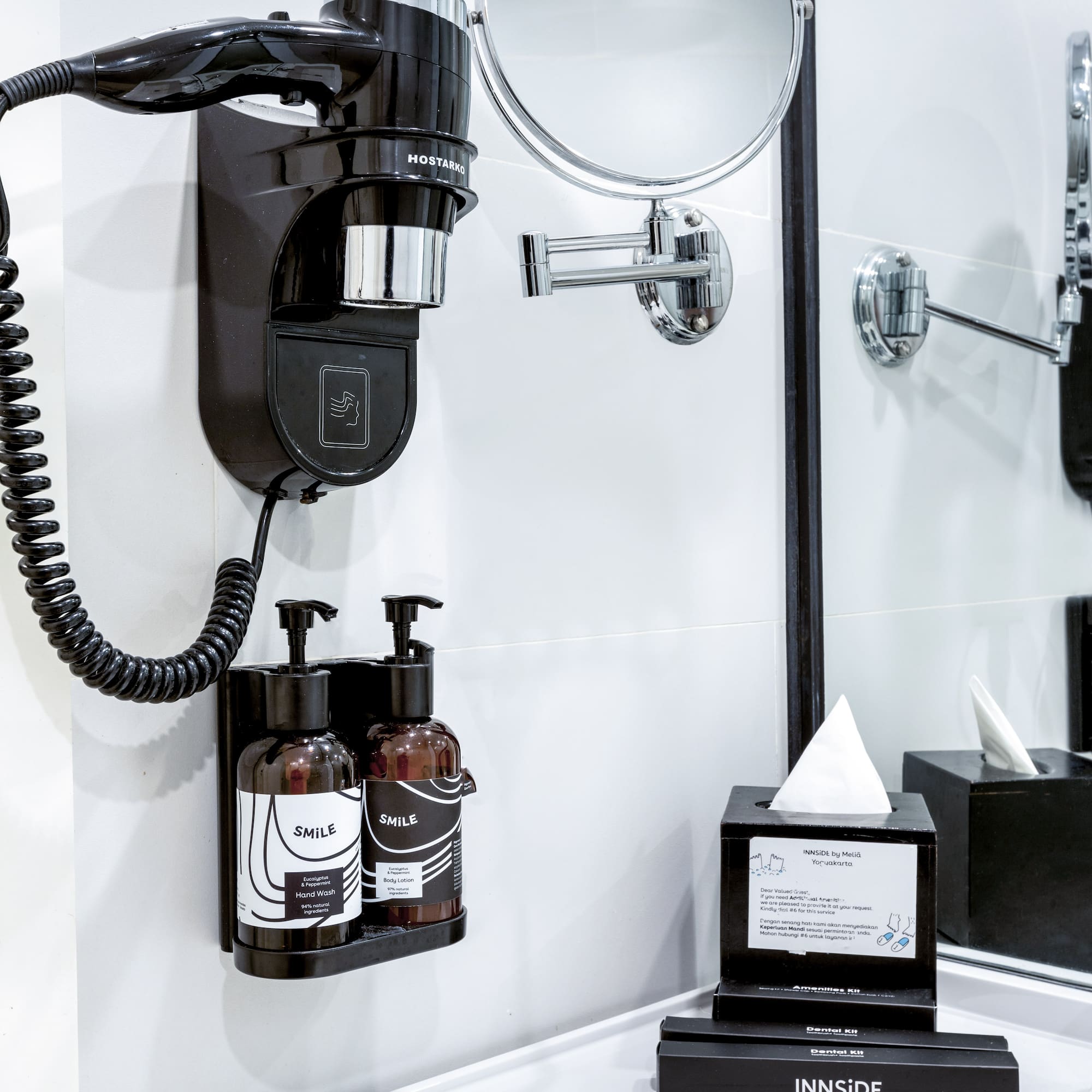 a black and white bathroom with a mirror and a black wall mounted hair dryer