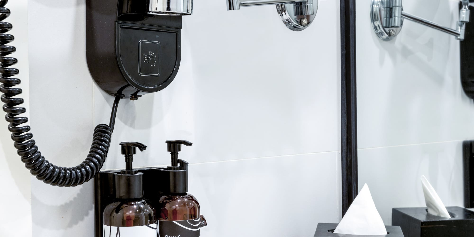 a black and white bathroom with a mirror and a black wall mounted hair dryer