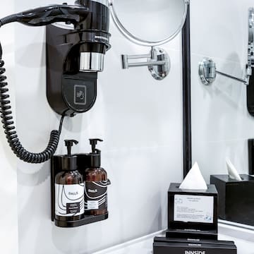 a black and white bathroom with a mirror and a black wall mounted hair dryer