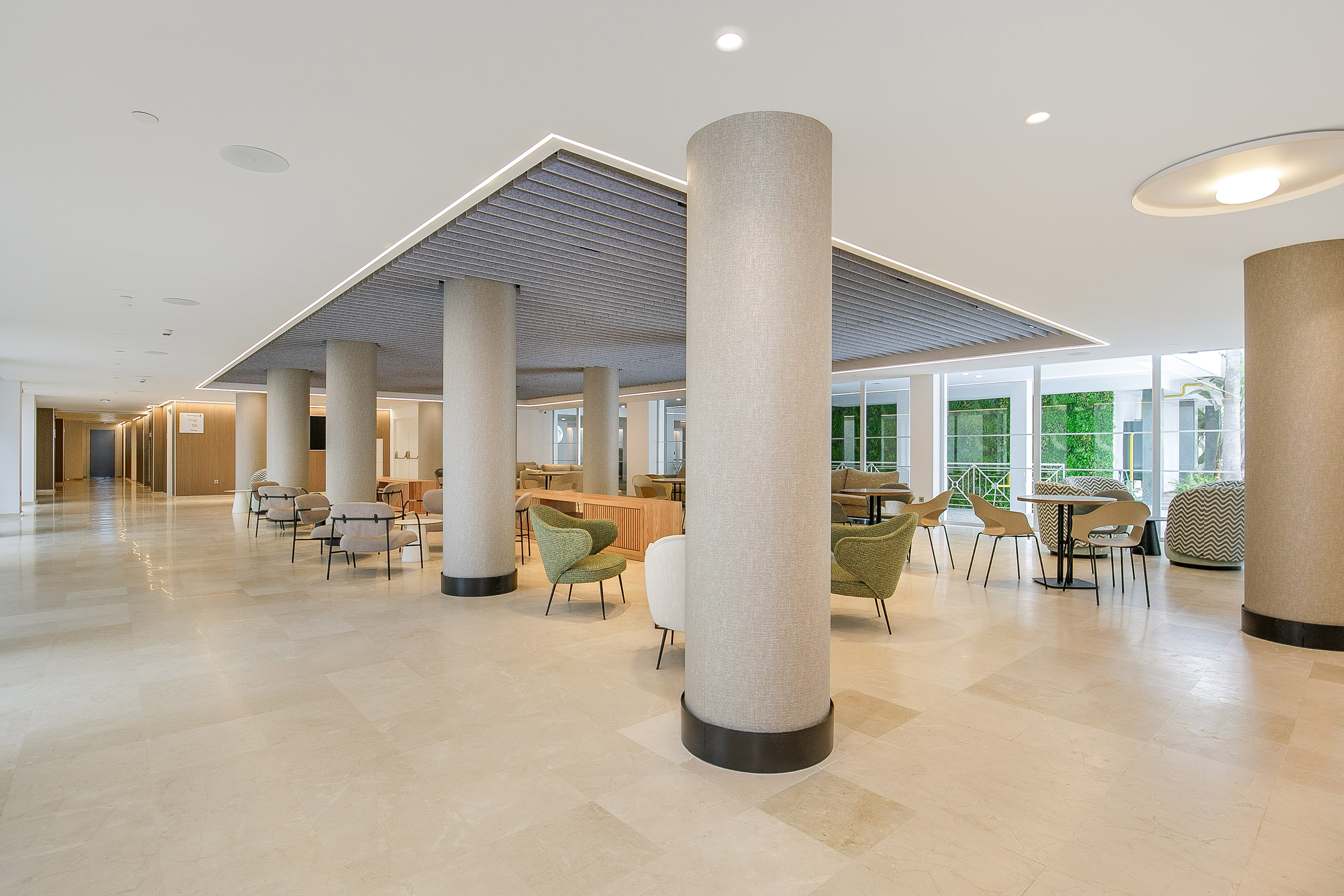 Spacious modern hotel lobby with diverse seating, fabric pillars, and marble floor.