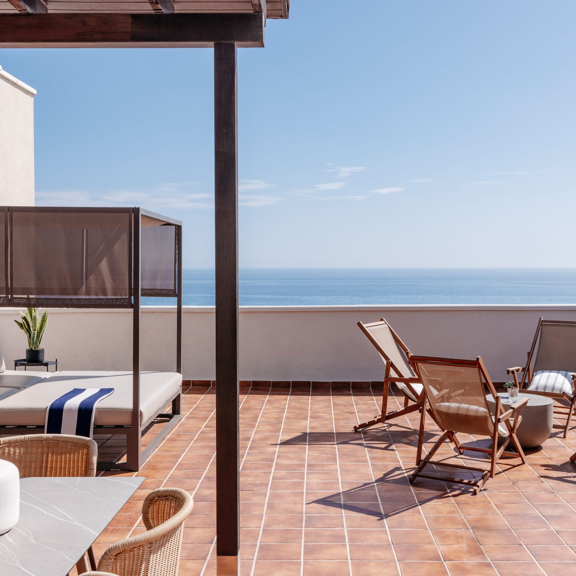 a patio with chairs and a table on a tile floor
