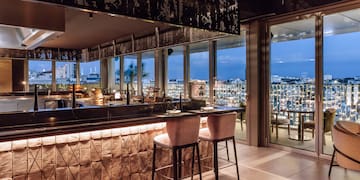 a bar with chairs and a view of the city from the window