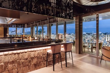 a bar with chairs and a view of a city