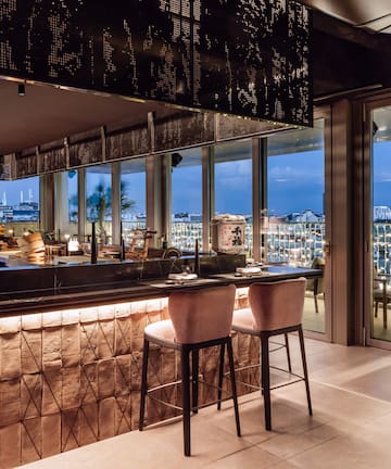 a bar with chairs and a view of the city from the window