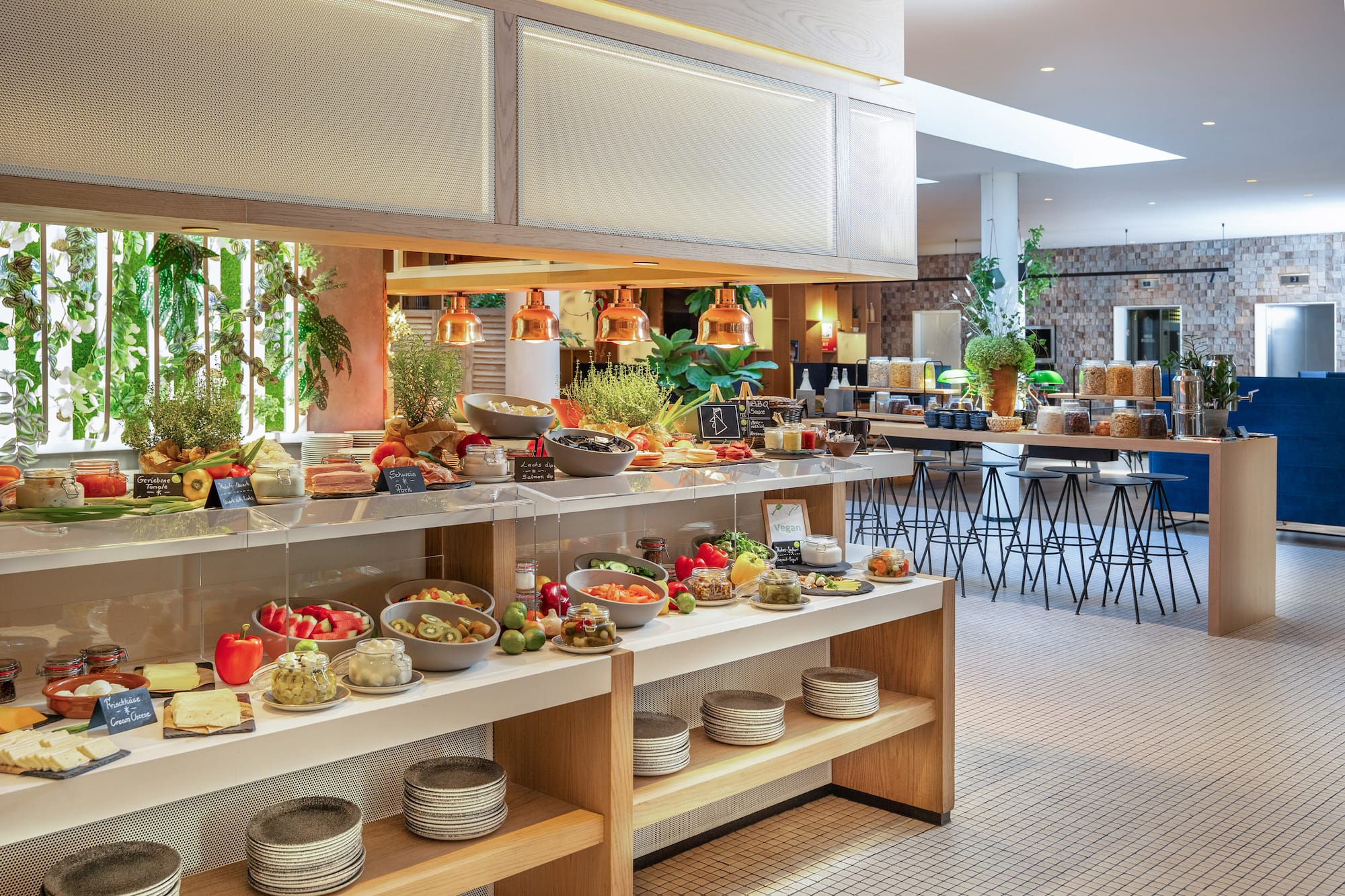 Fresh breakfast buffet with cheeses, fruits, and meats in a modern hotel.