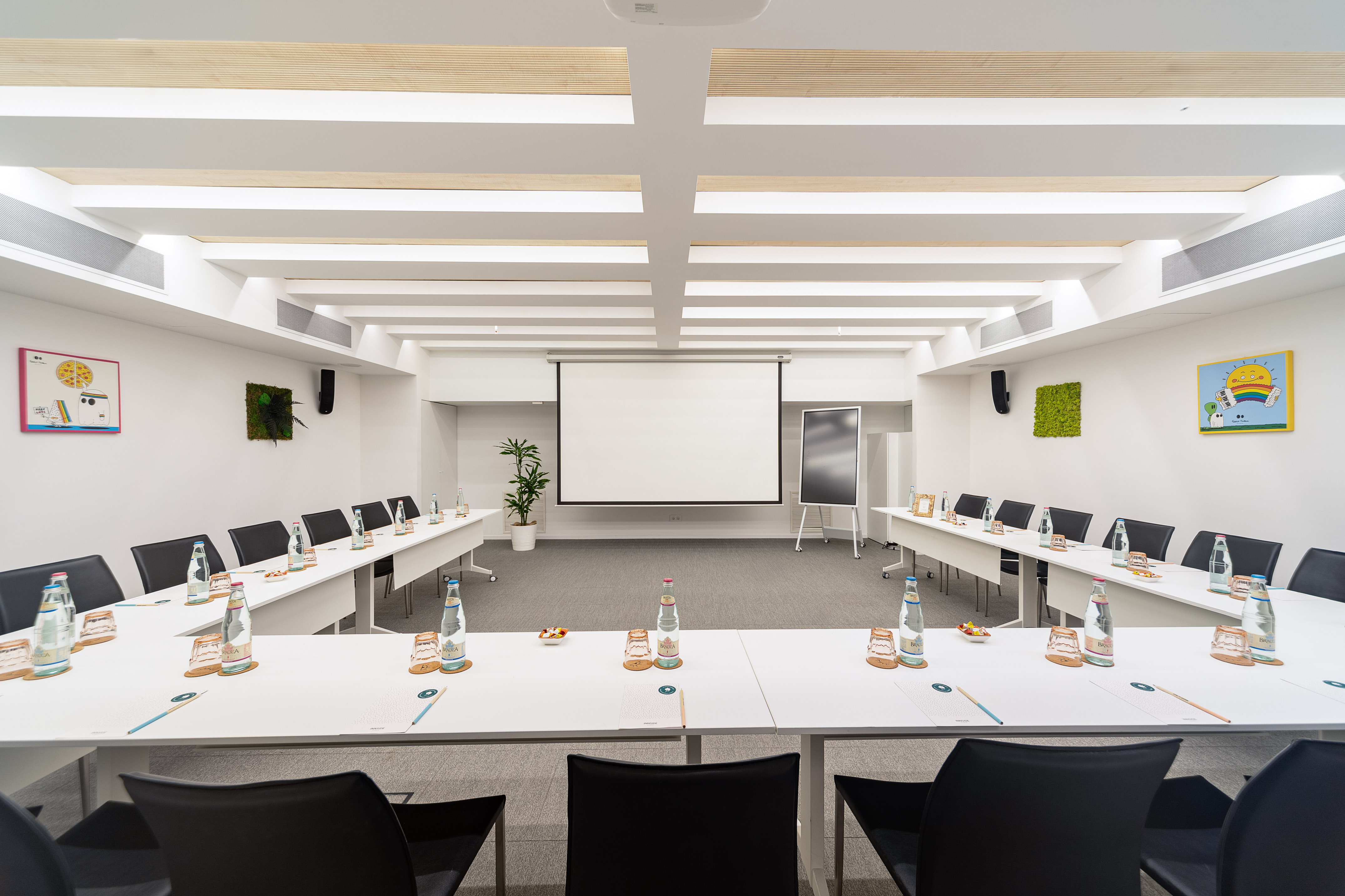 Modern U-shaped conference room with projector, tables, and individual settings.