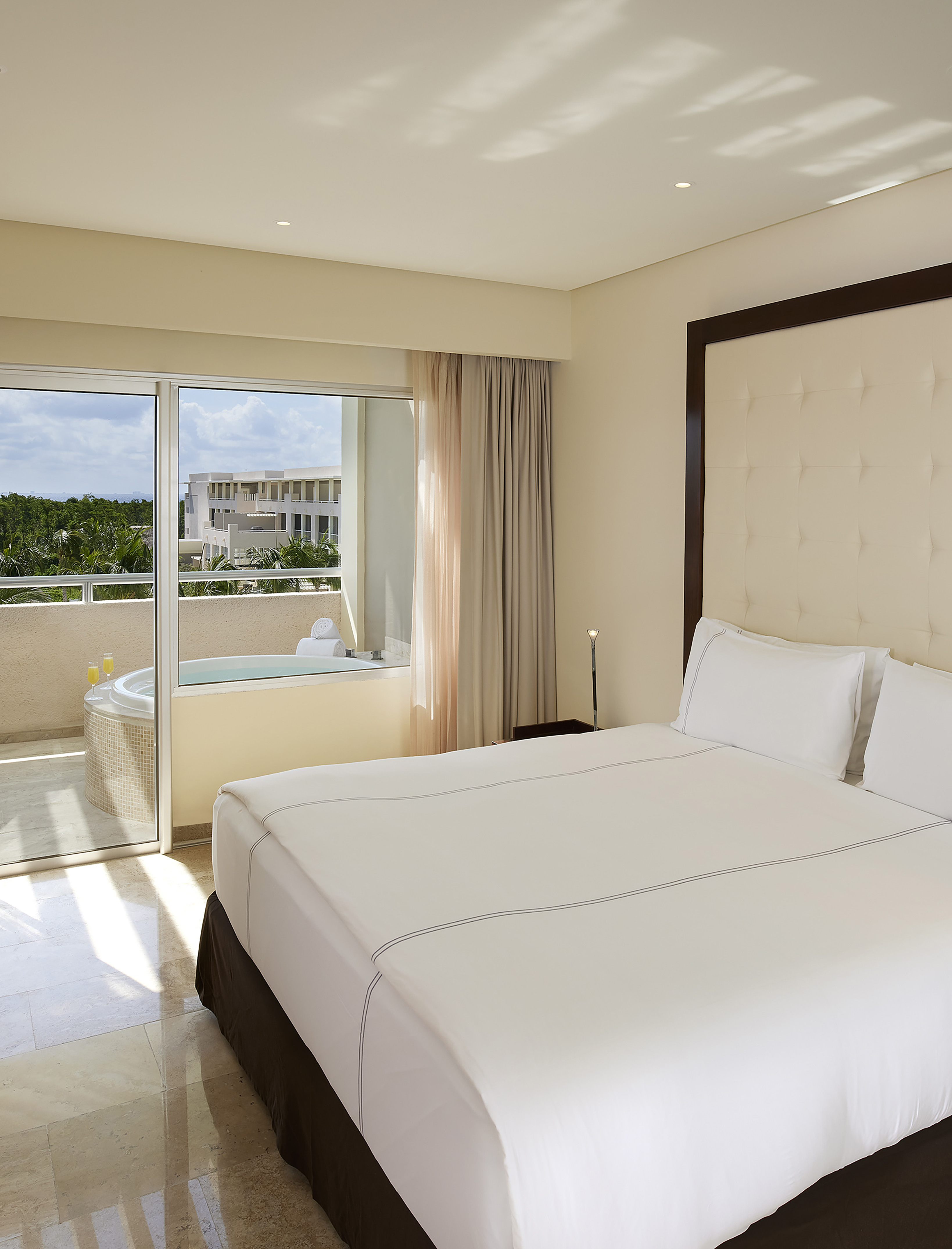 Spacious hotel suite with king bed, balcony jacuzzi, and scenic resort view.