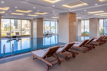 a pool with chairs in a room with windows and a city view
