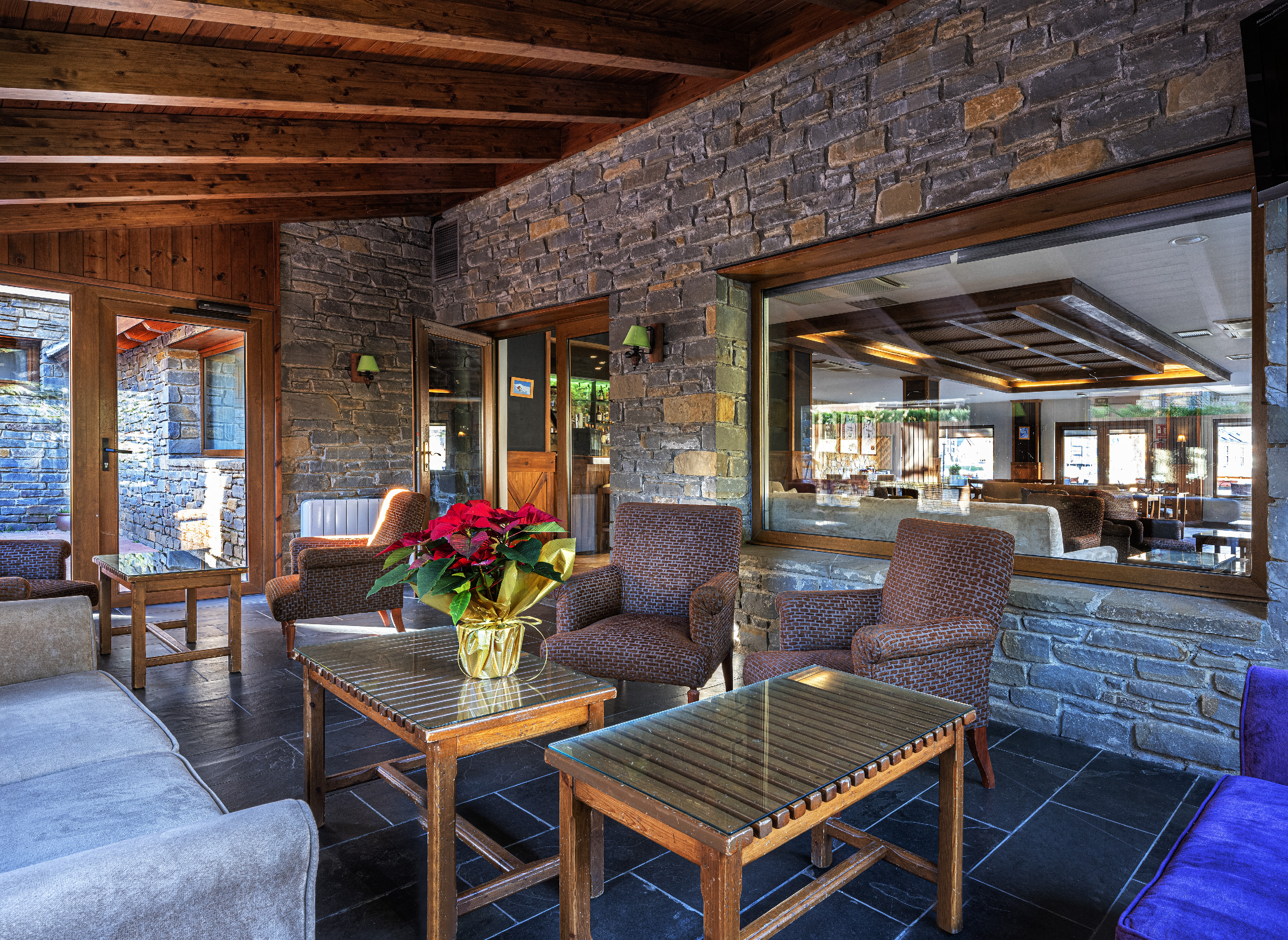 Rustic hotel lounge featuring stone walls, wood beams, and comfortable seating.