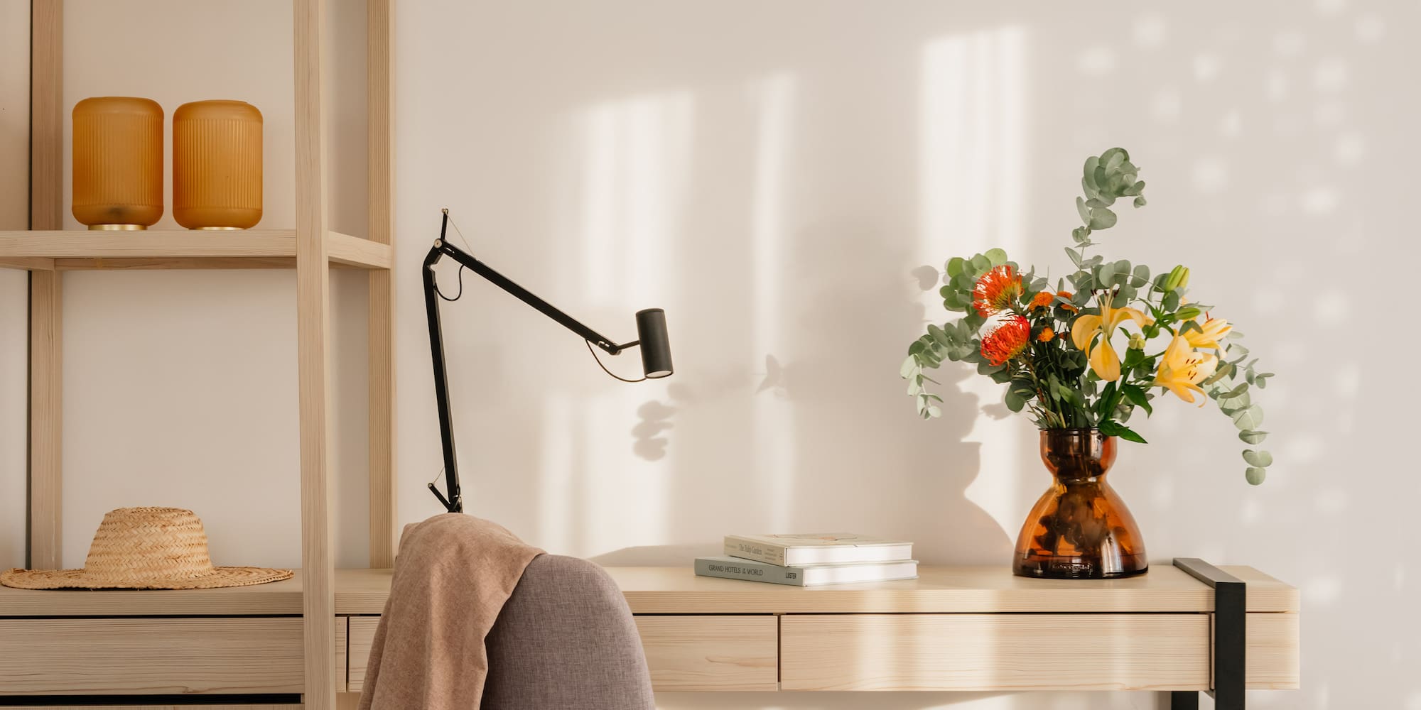 a desk with a chair and a vase of flowers