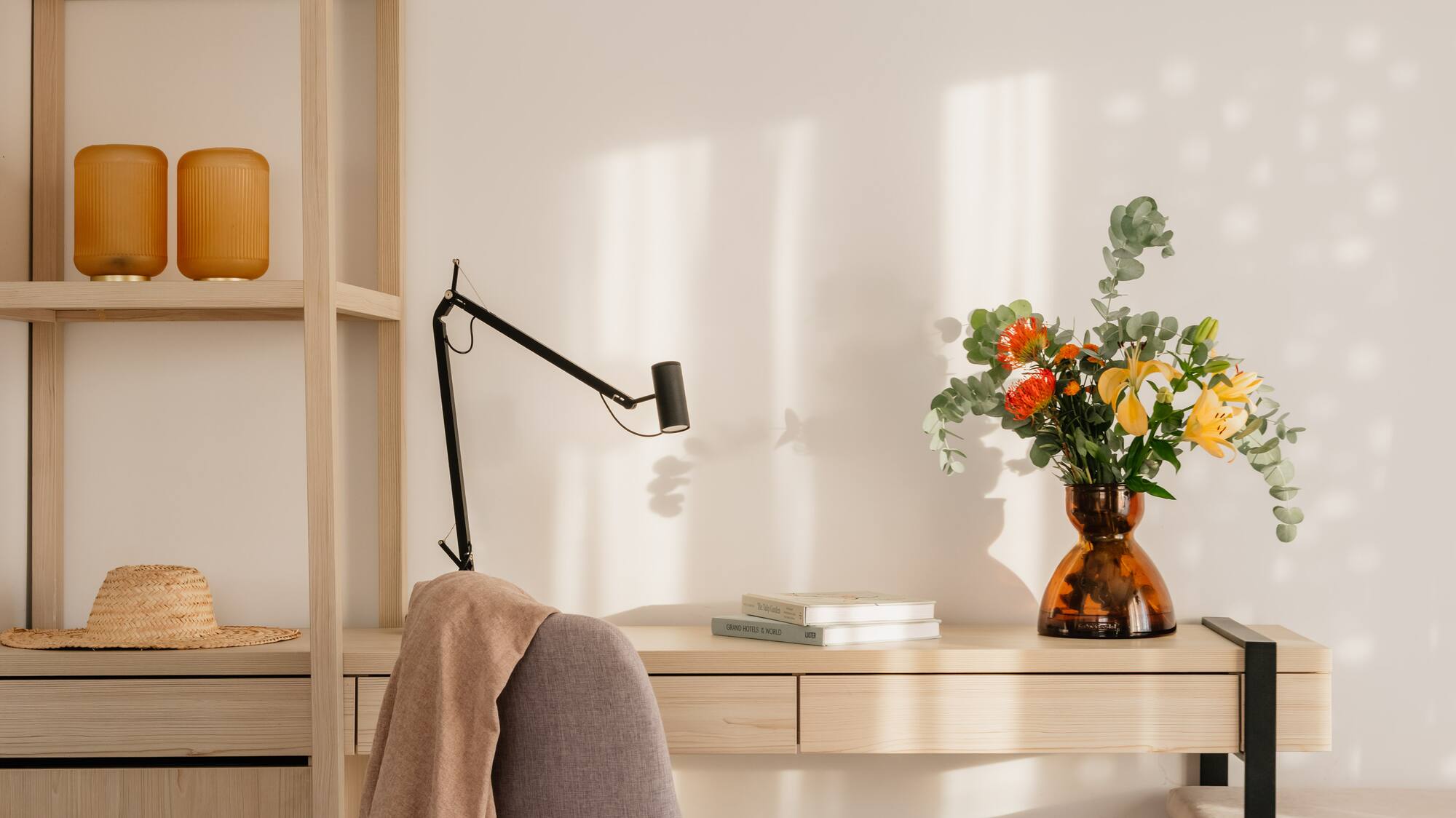 a desk with a chair and a vase of flowers