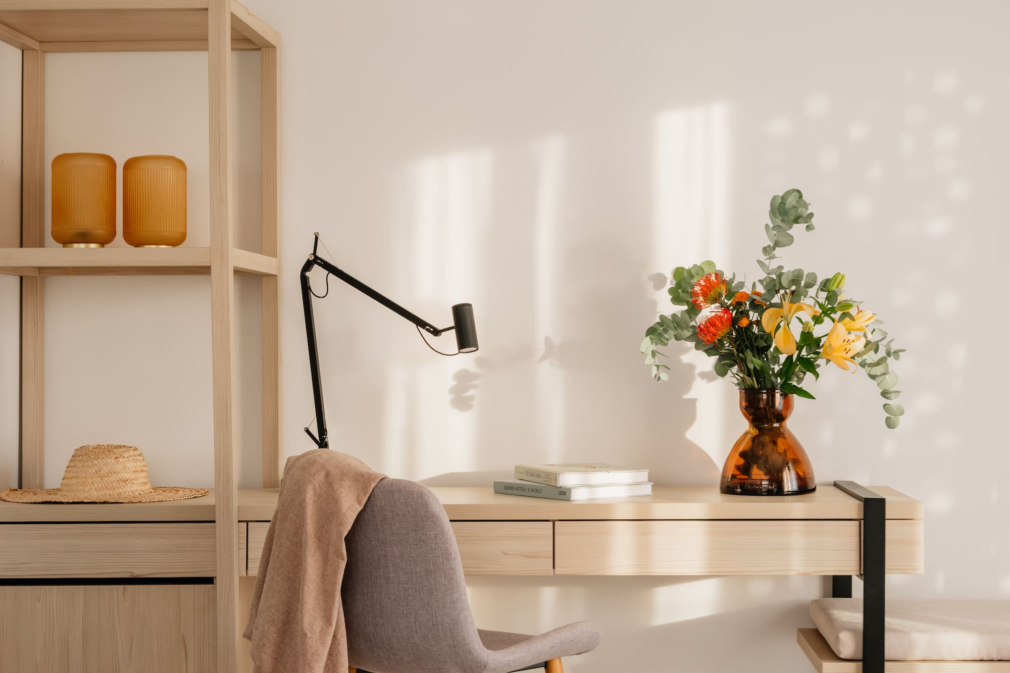 a desk with a chair and a vase of flowers