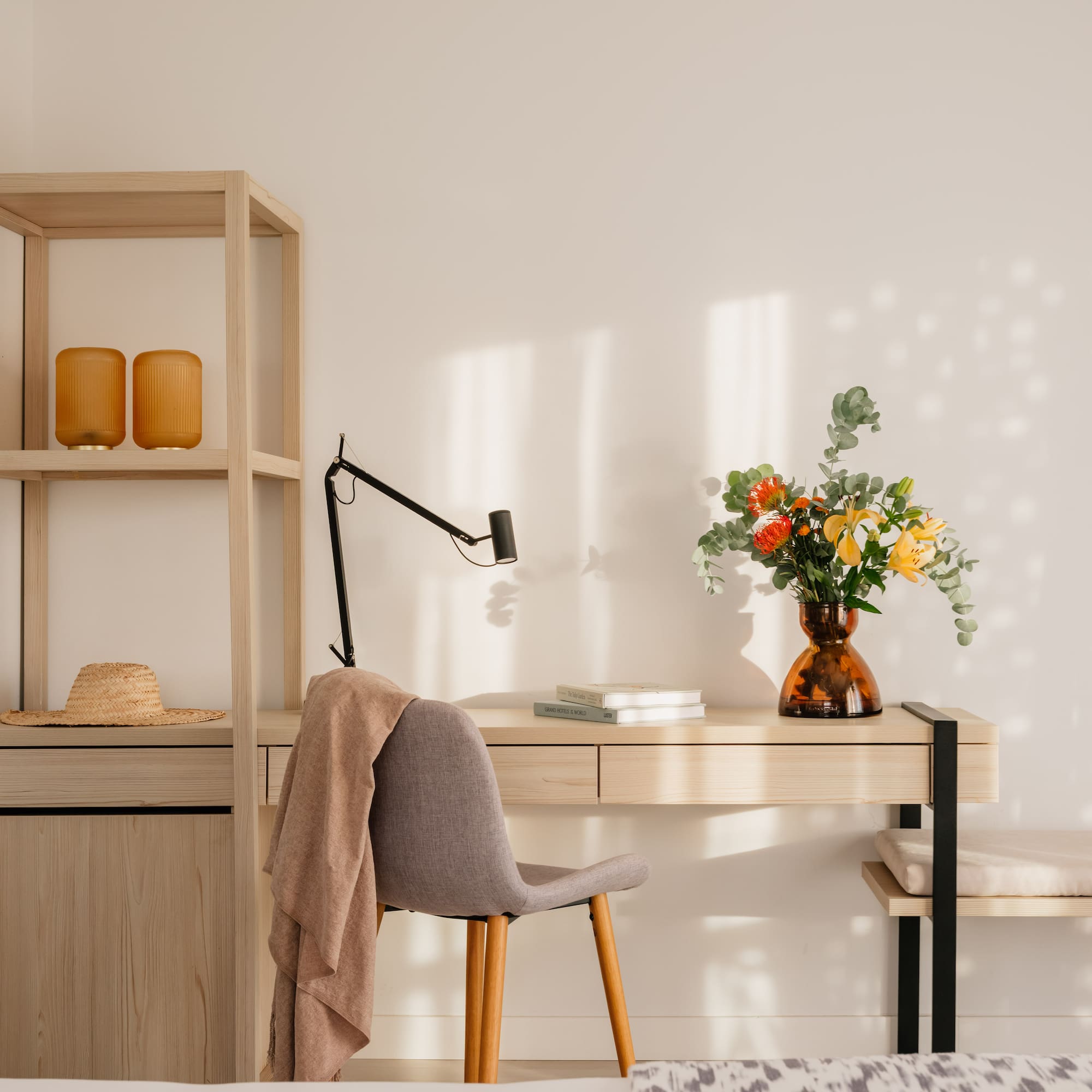 a desk with a chair and a vase of flowers