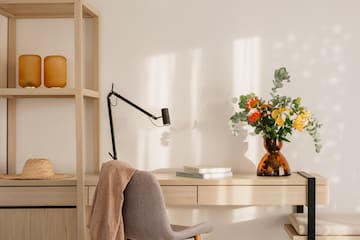 a desk with a chair and a vase of flowers
