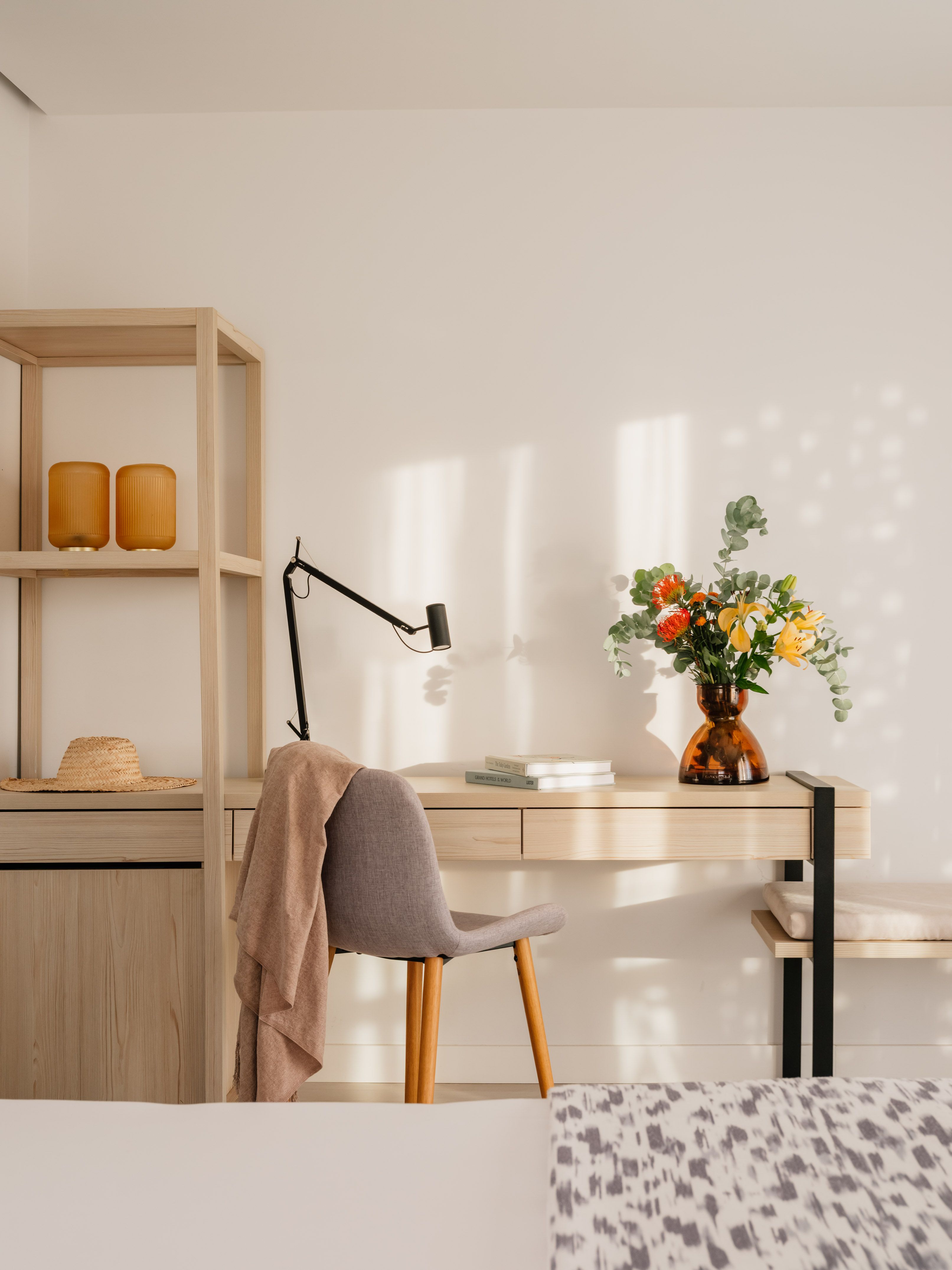 a desk with a chair and a vase of flowers