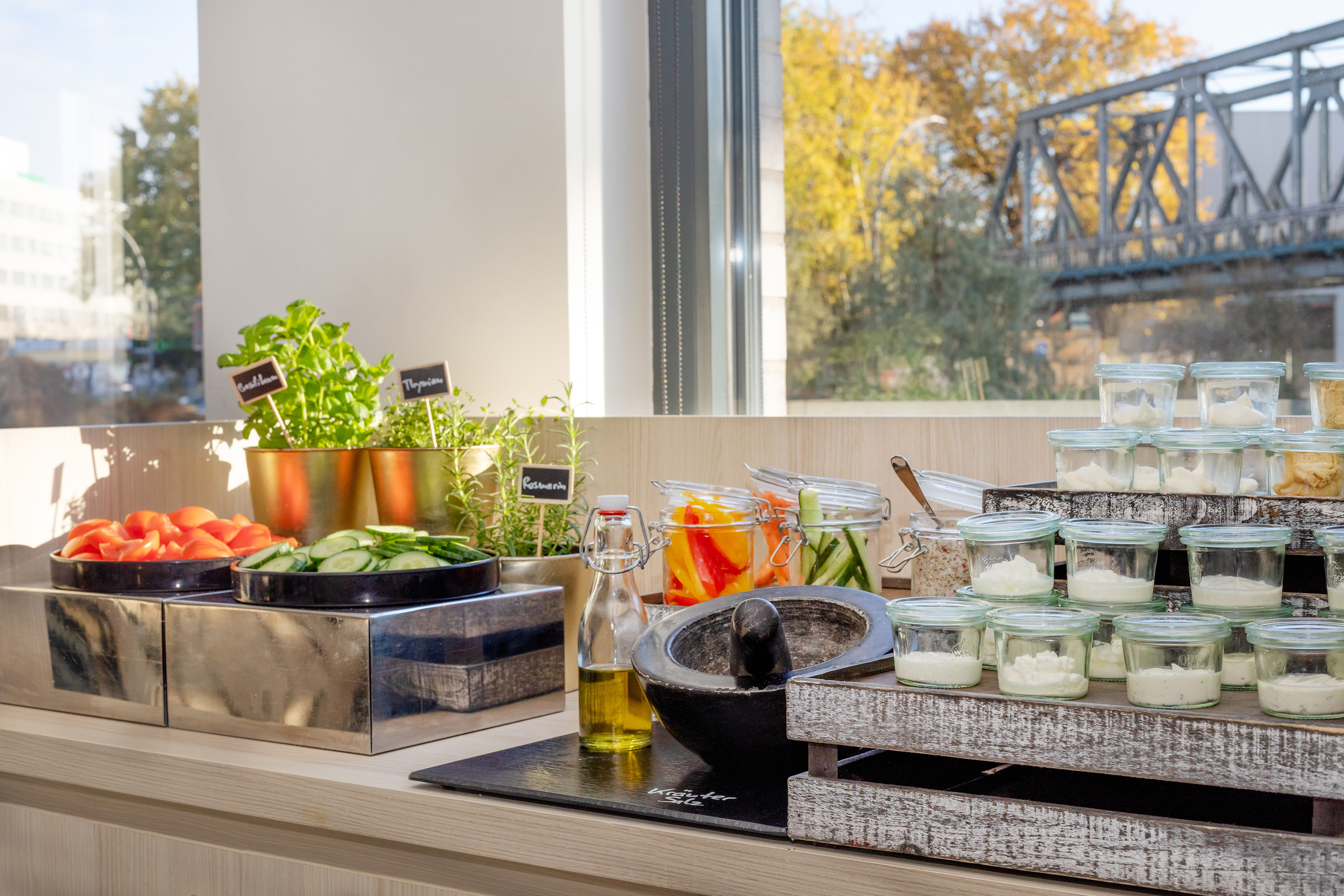 Fresh salad bar buffet with herbs, sliced vegetables, olive oil, and sauces.