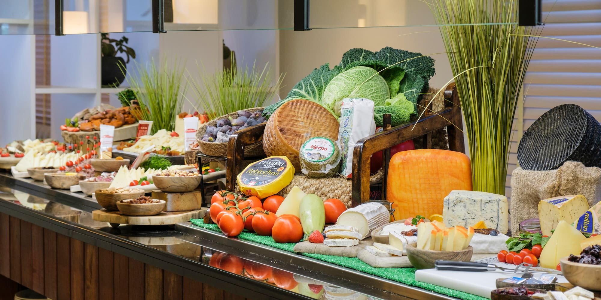 Gourmet cheese buffet featuring various cheeses, fresh fruits, and vegetables.