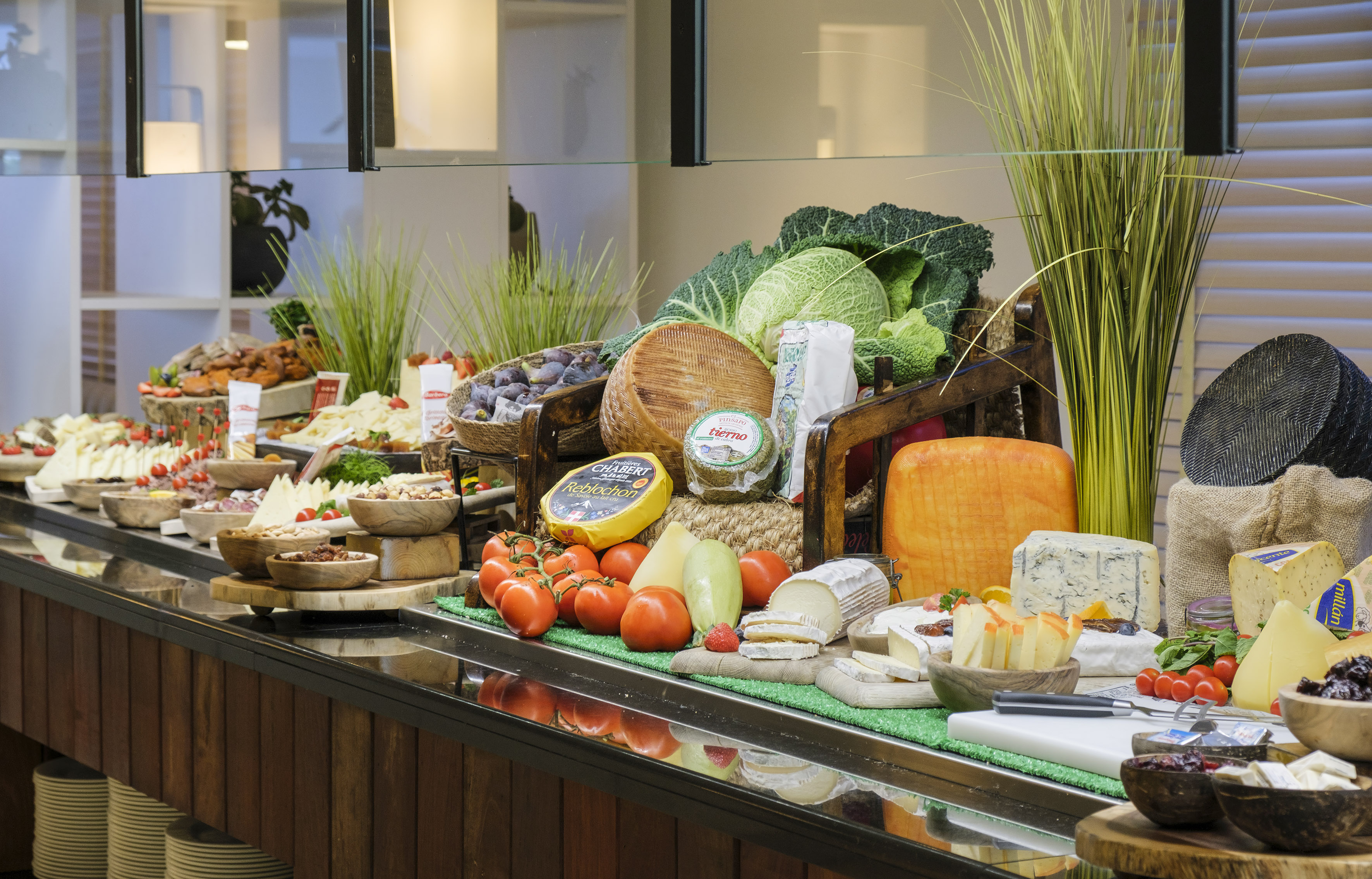 Gourmet cheese buffet featuring various cheeses, fresh fruits, and vegetables.
