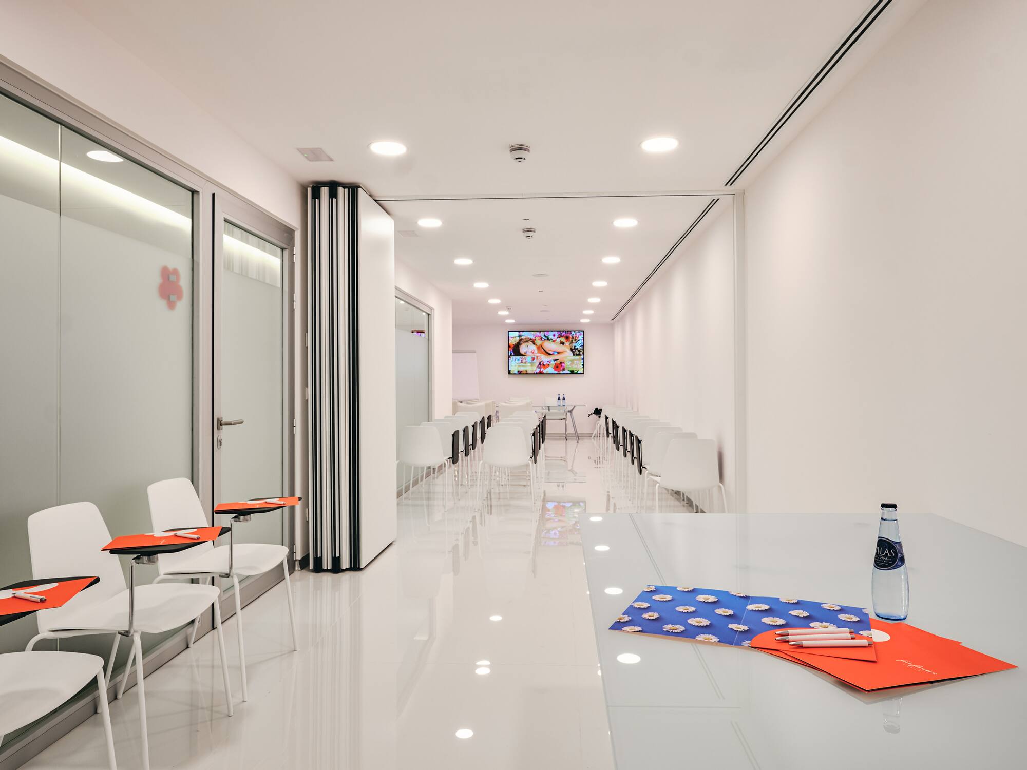 a room with white walls and a white table with chairs and a tv