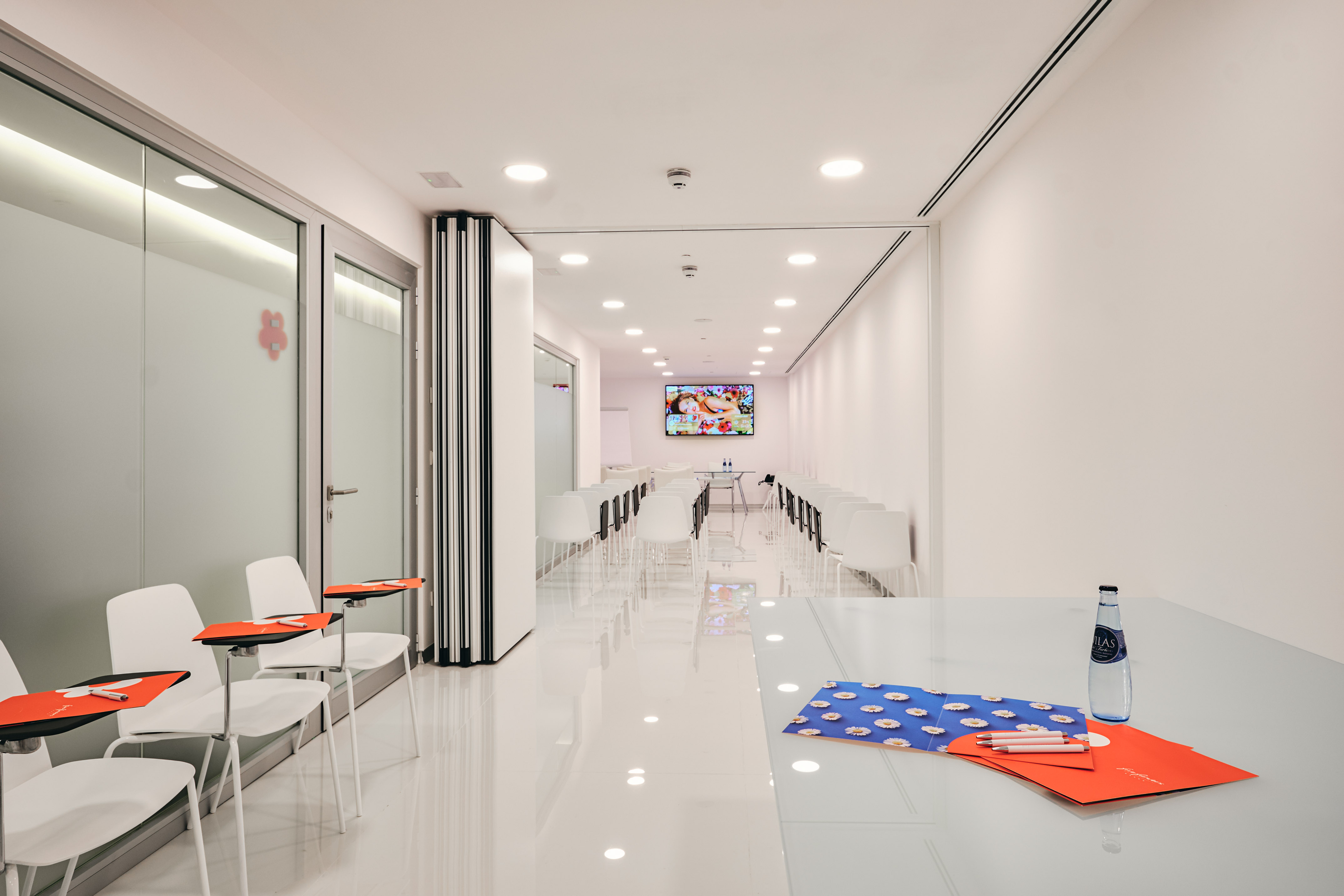 Bright clinic training room with white chairs and presentation screen.