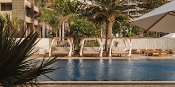 a pool with chairs and umbrellas by a building