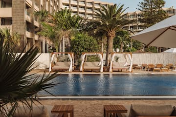a pool with chairs and umbrellas by a building