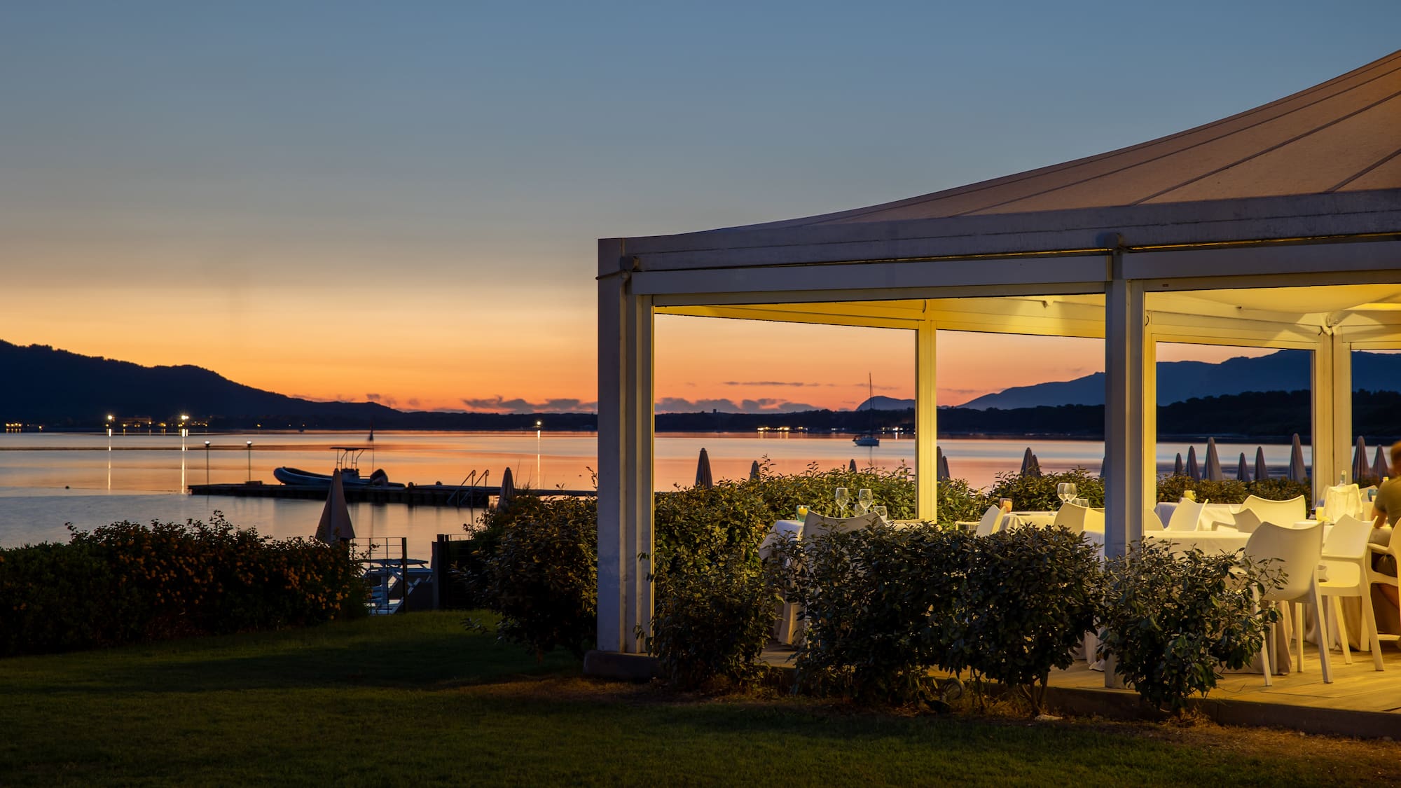 a white structure with a view of a body of water and a sunset