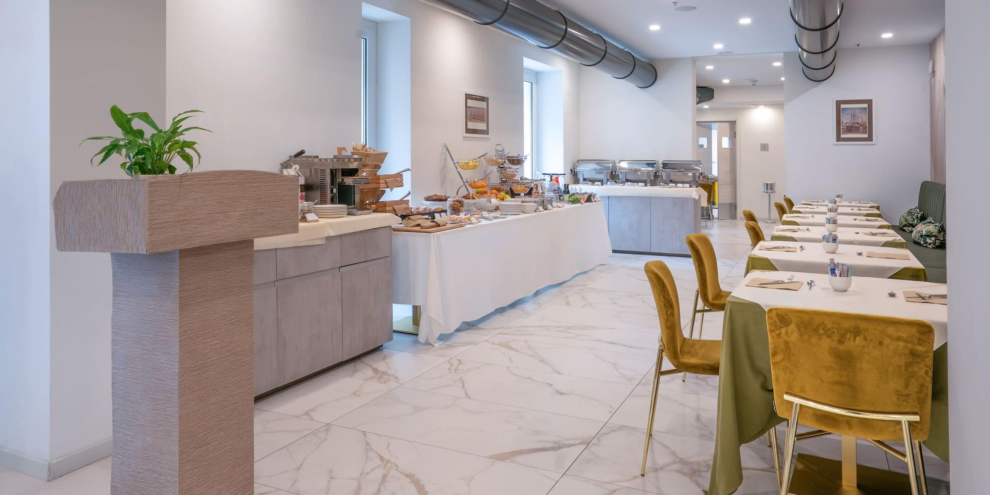 Modern hotel breakfast buffet with elegant dining tables and golden chairs.