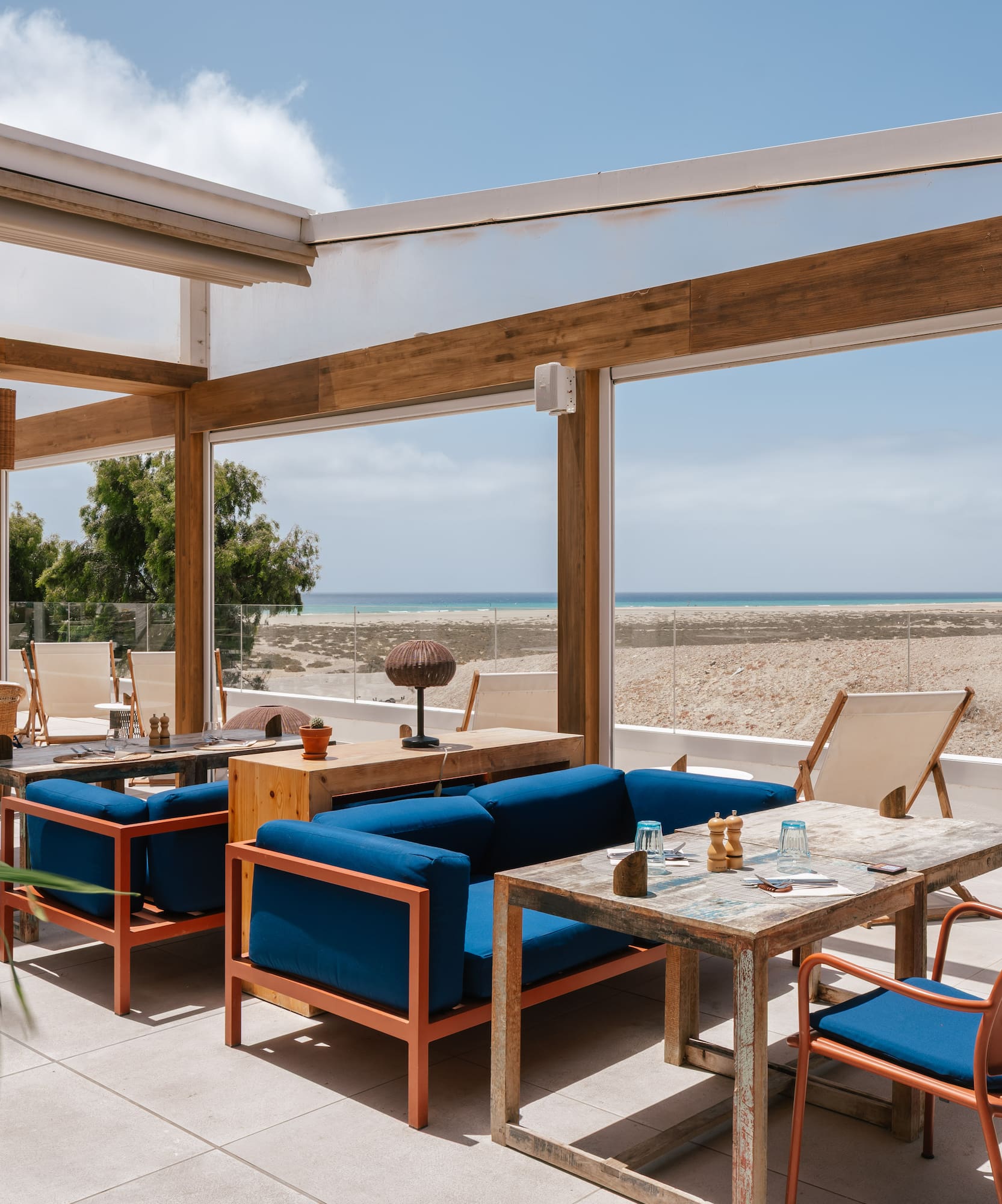 Coastal restaurant terrace with blue modern seating and ocean view.