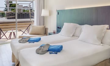 a room with two beds with white sheets and sandals on it
