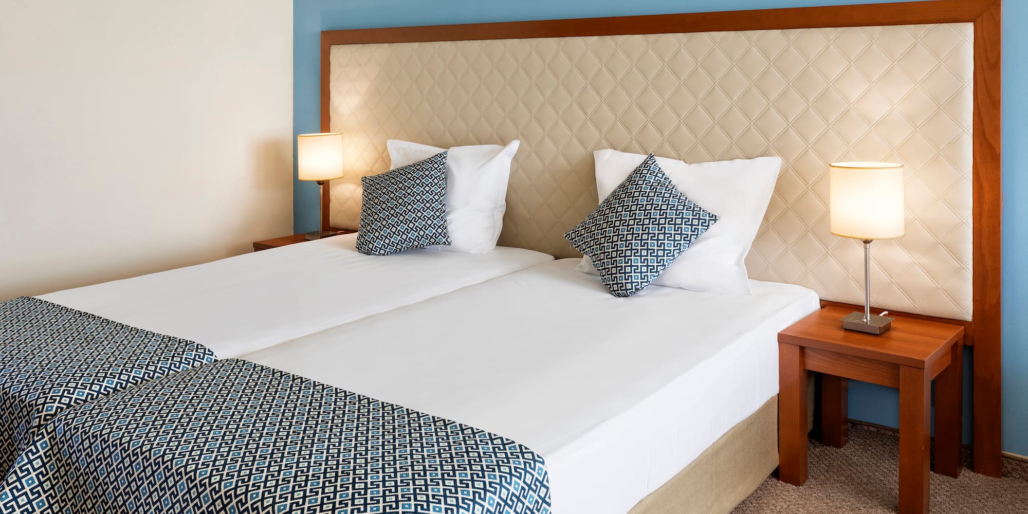 a bed with two pillows and a table with lamps