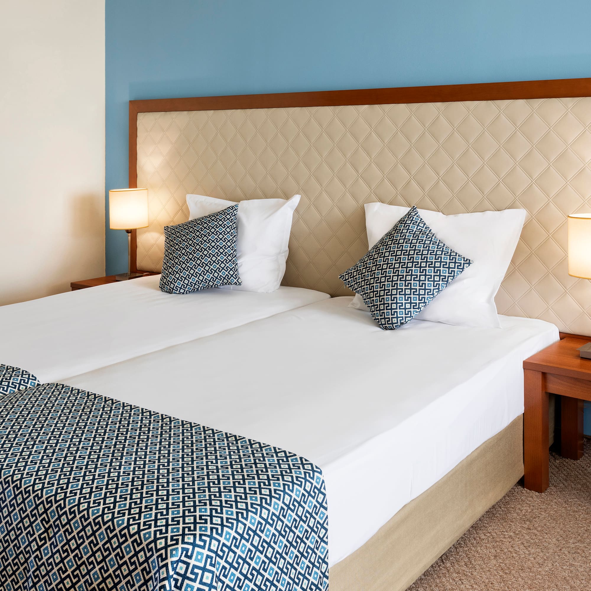 a bed with two pillows and a table with lamps