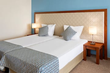 a bed with two pillows and a table with lamps