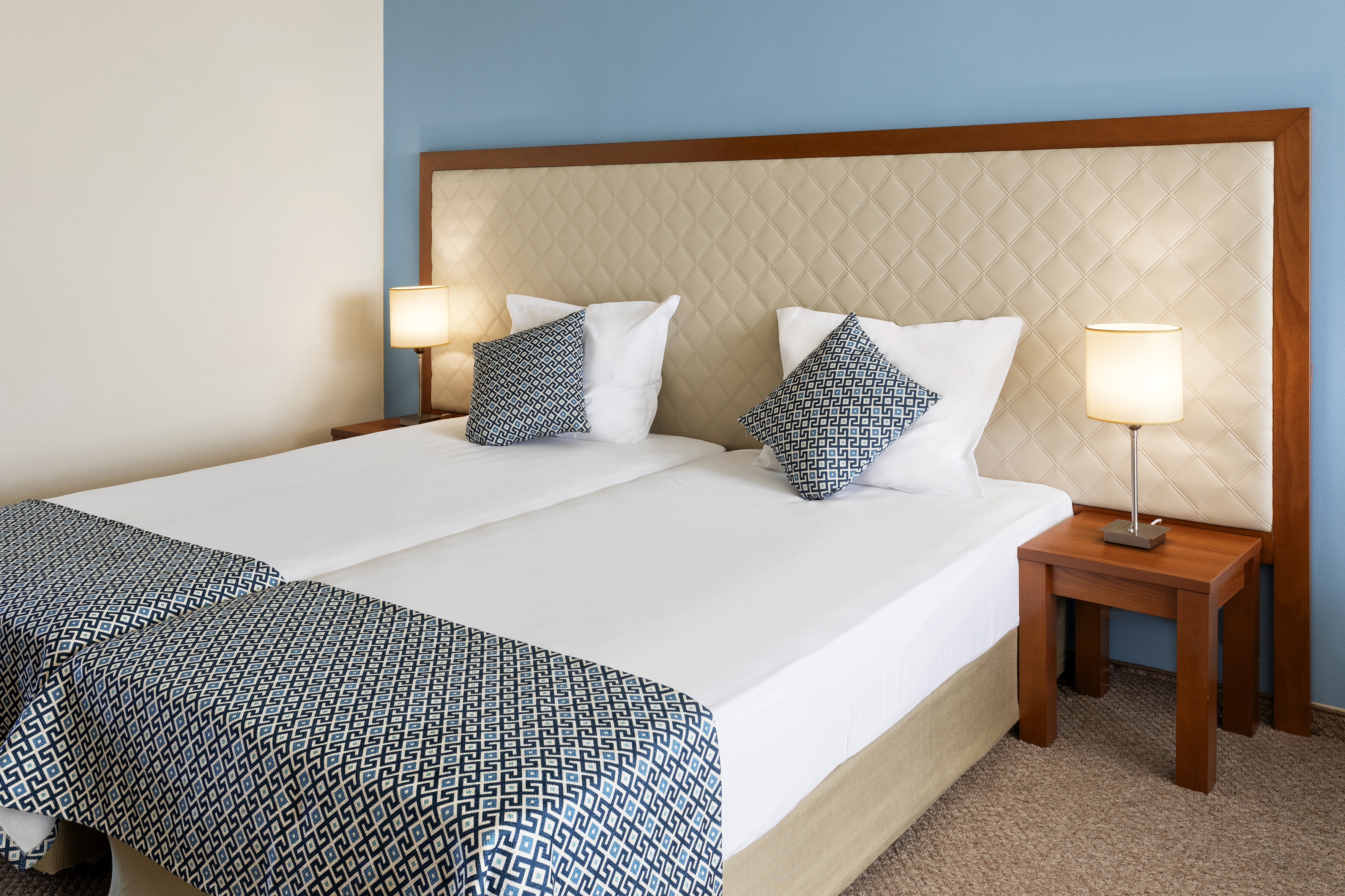 a bed with two pillows and a table with lamps