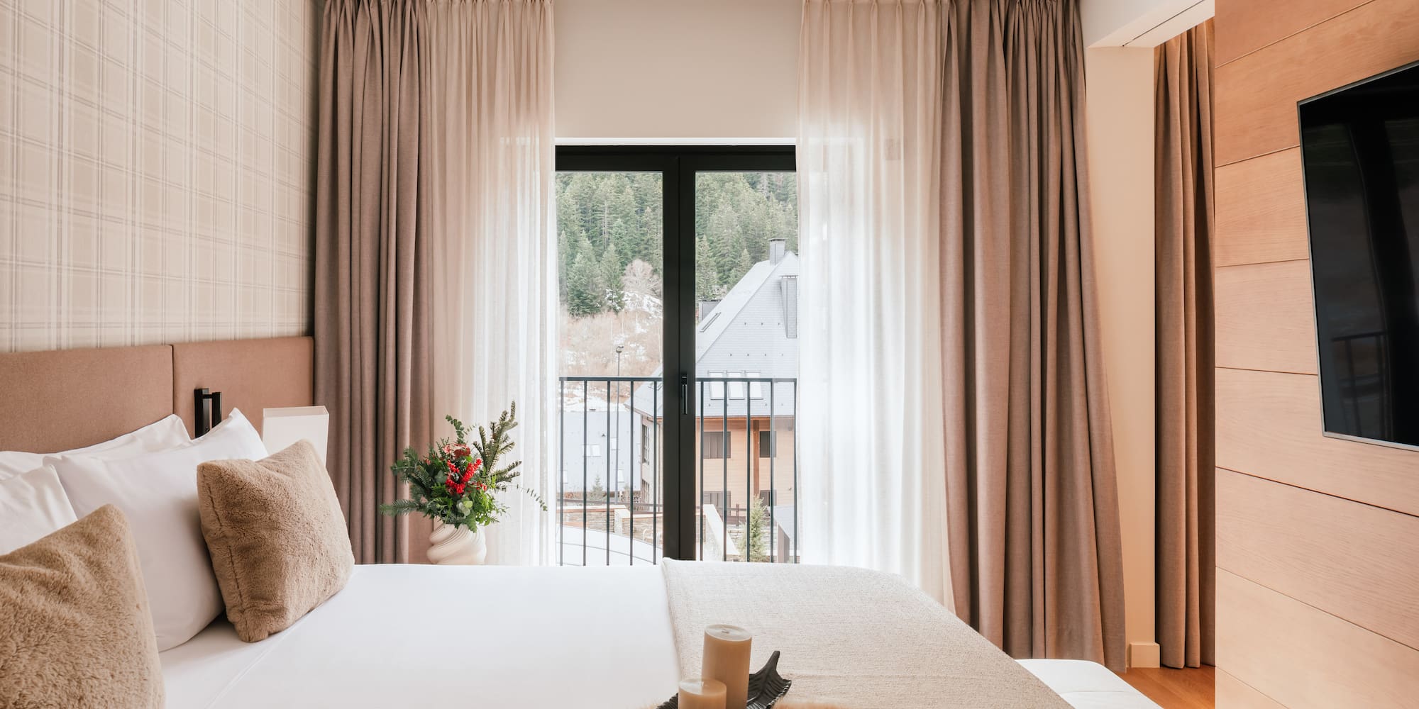 Modern hotel room with mountain view balcony, soft bed, and winter details.