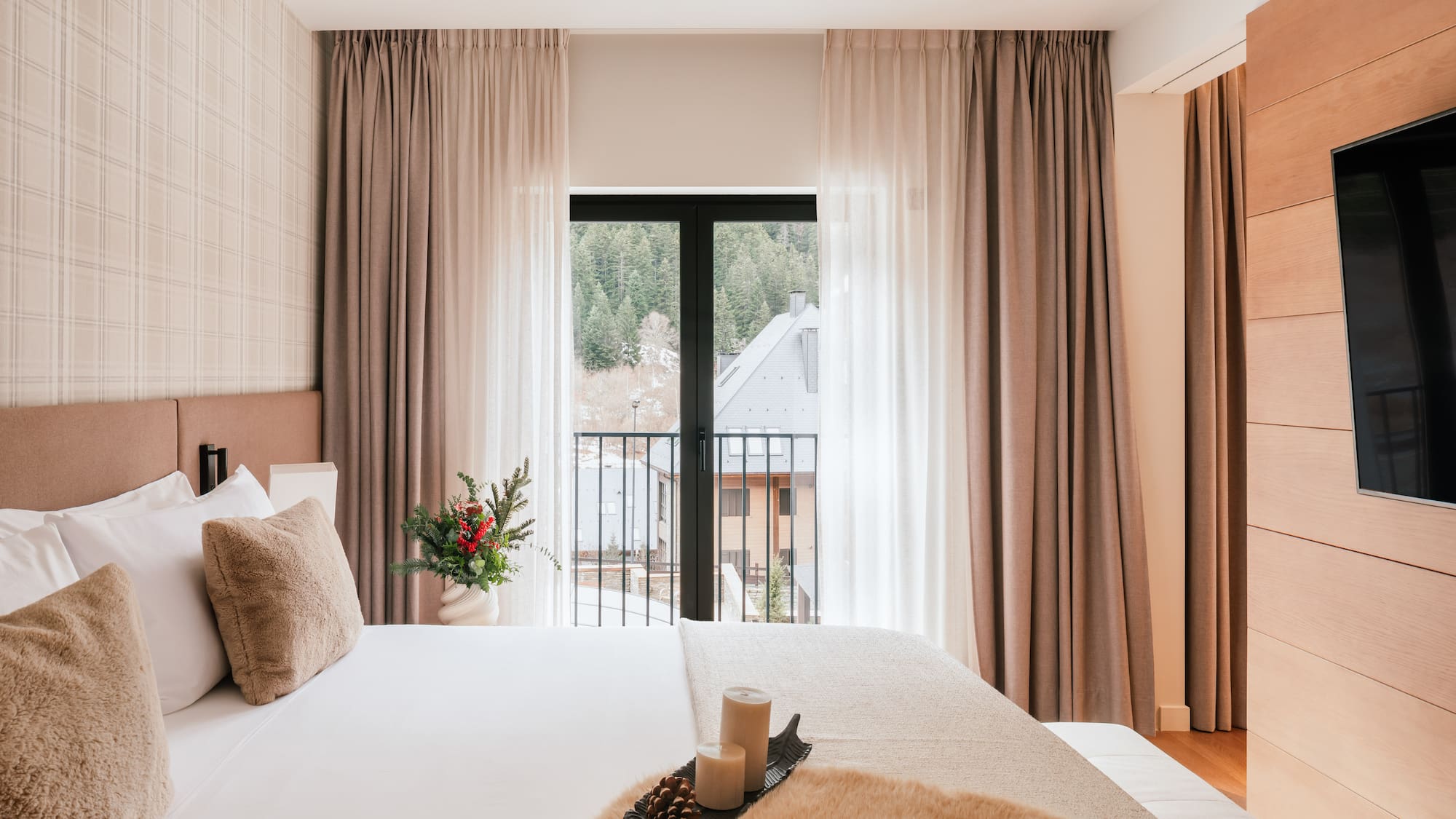 Modern hotel room with mountain view balcony, soft bed, and winter details.