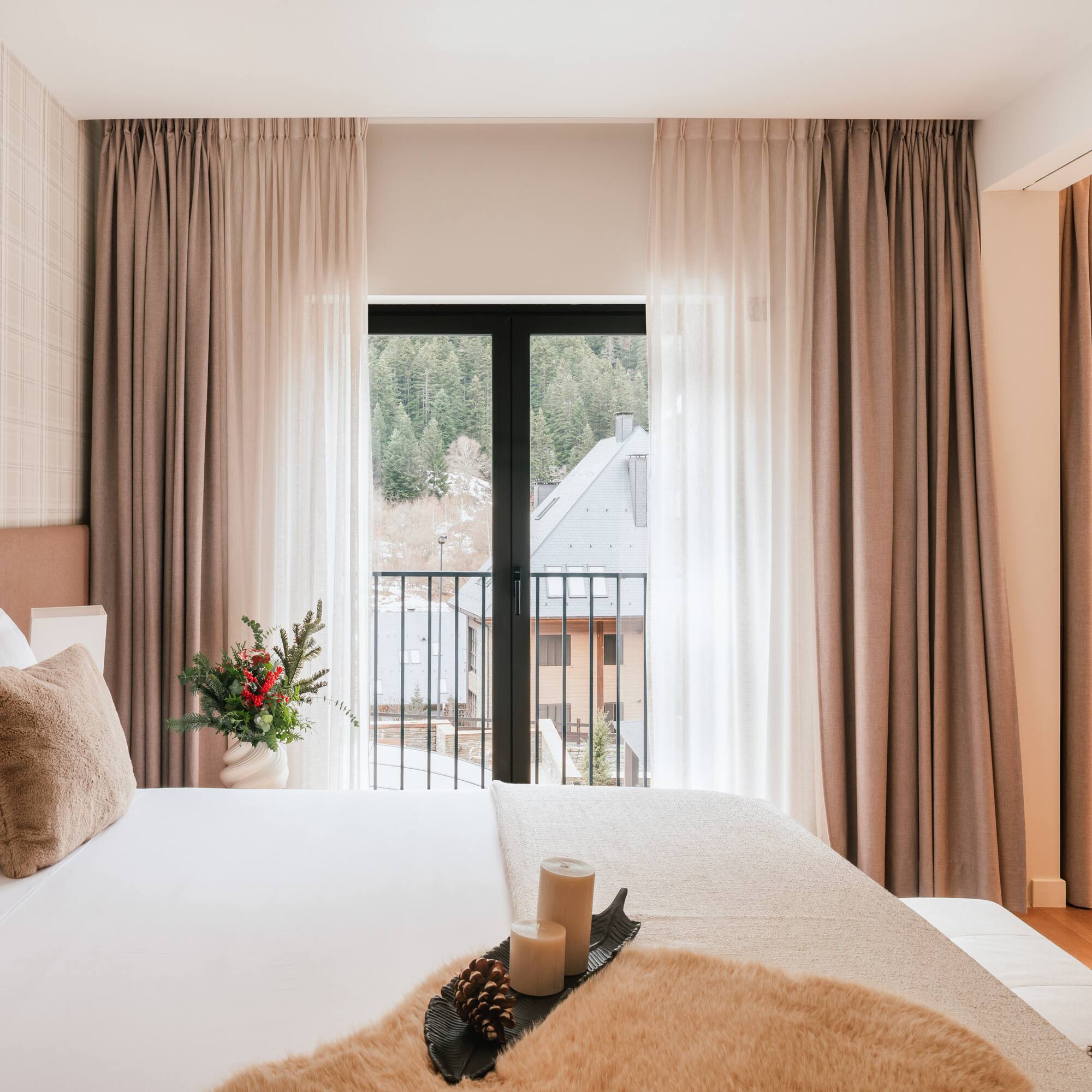 Modern hotel room with mountain view balcony, soft bed, and winter details.