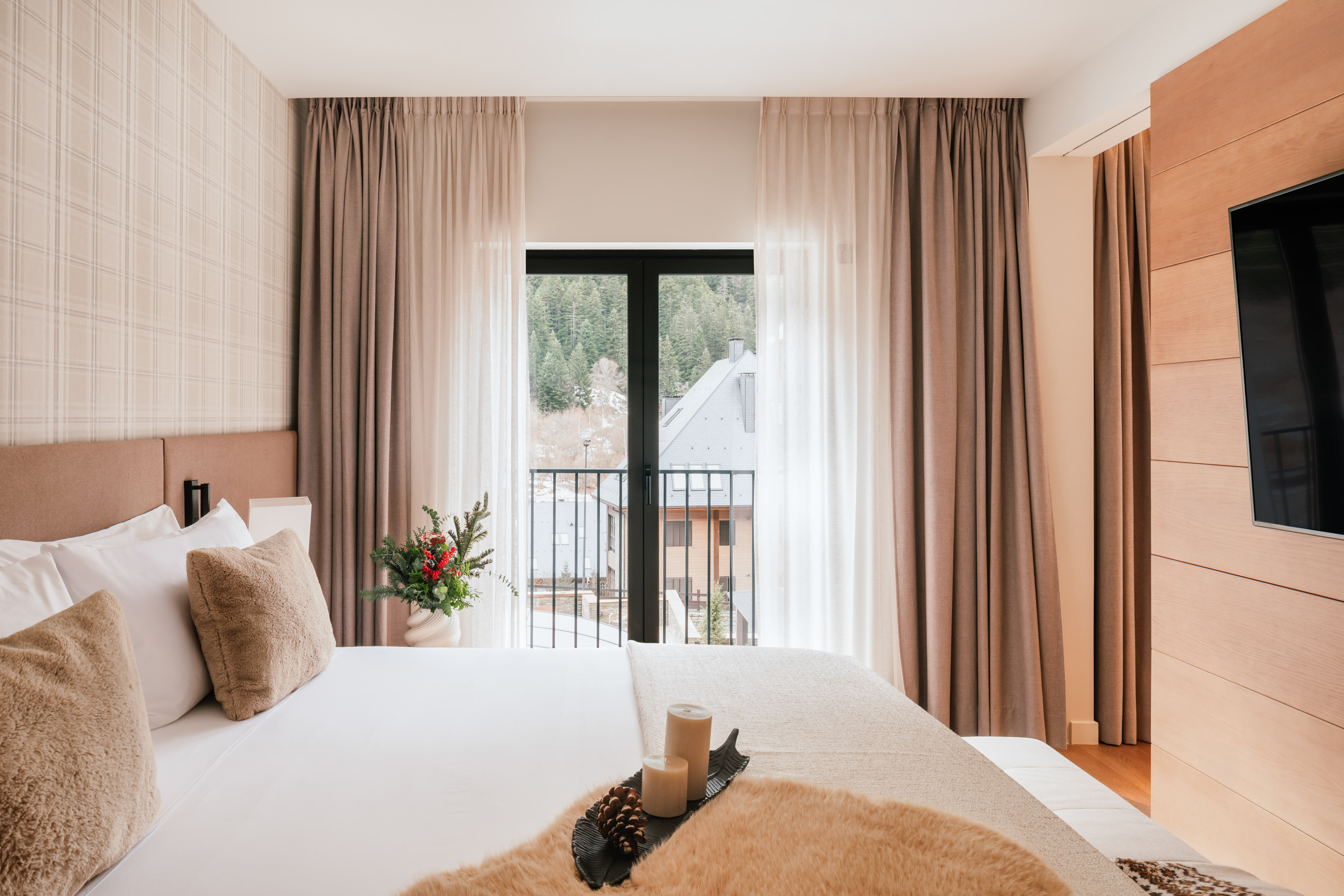 Modern hotel room with mountain view balcony, soft bed, and winter details.