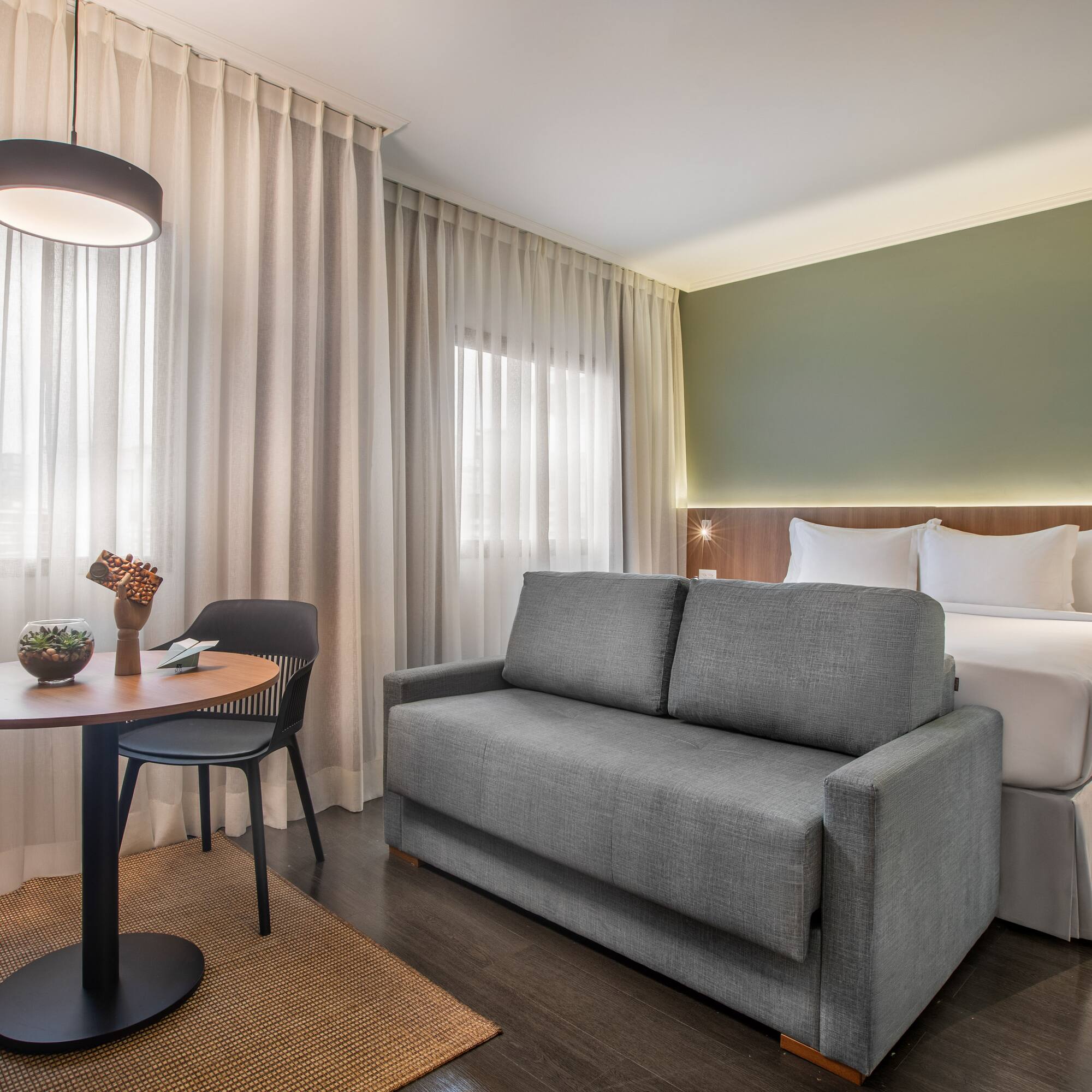 Habitación de hotel moderna con cama, sofá cama y zona de estar.